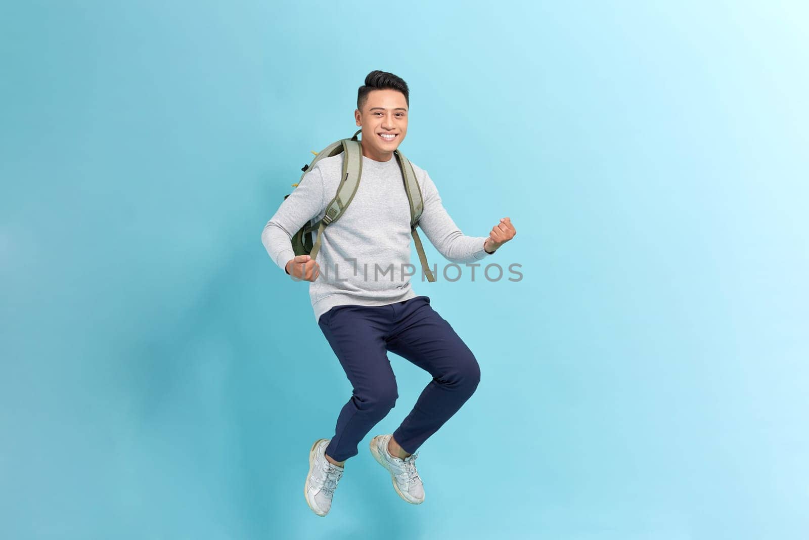 Happy young Asian man traveler running isolated on blue background