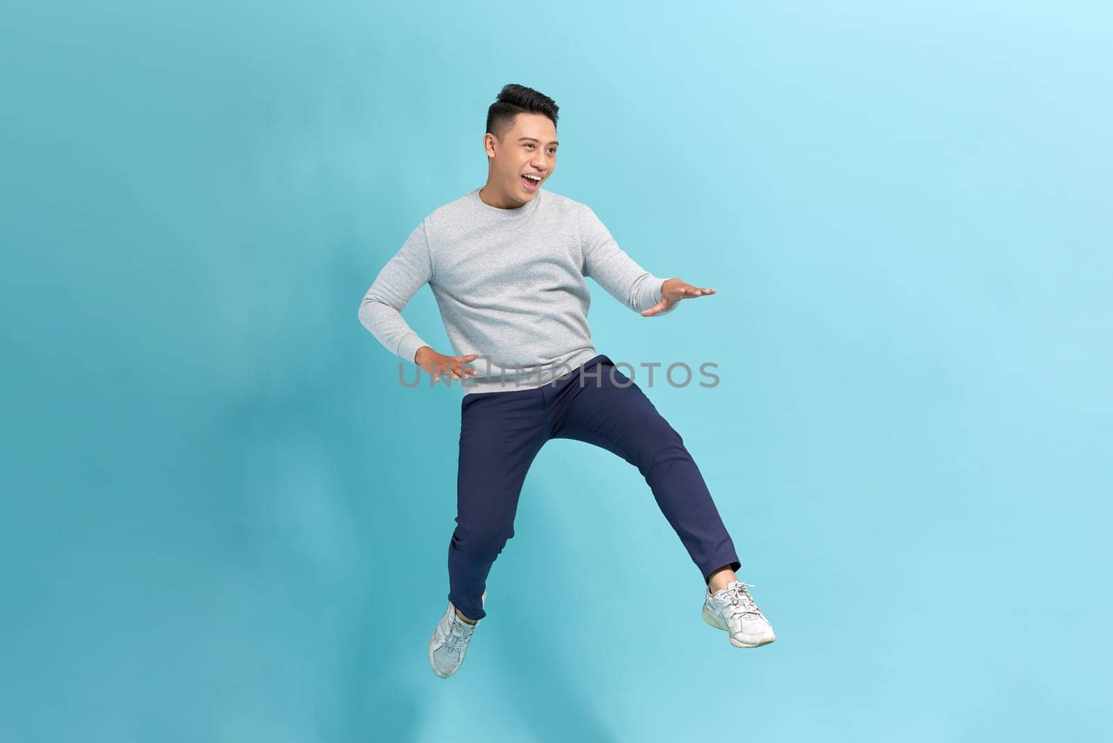 young guy jump wear shirt pants sneakers isolated on blue background