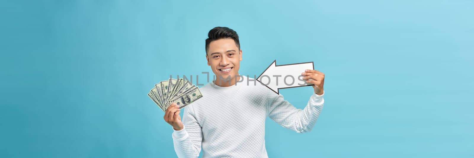 Happy winner man smiling and pointing arrow on fan of money banknotes