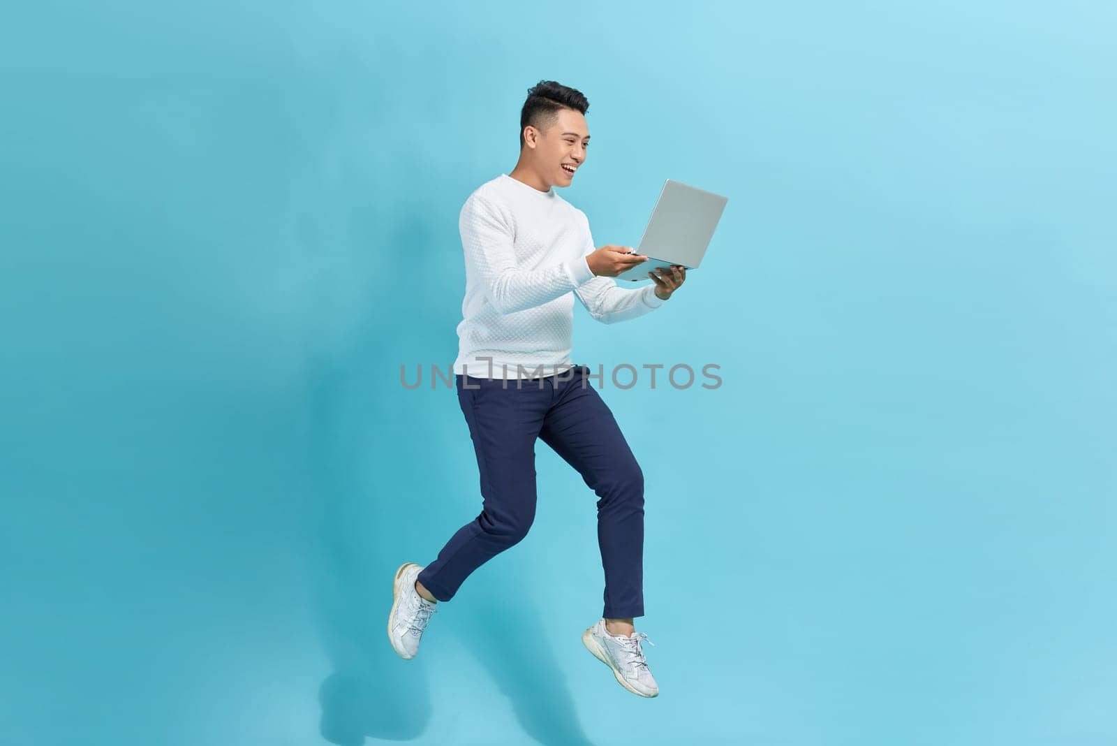 young man run jump hold laptop agent marketer isolated over blue background