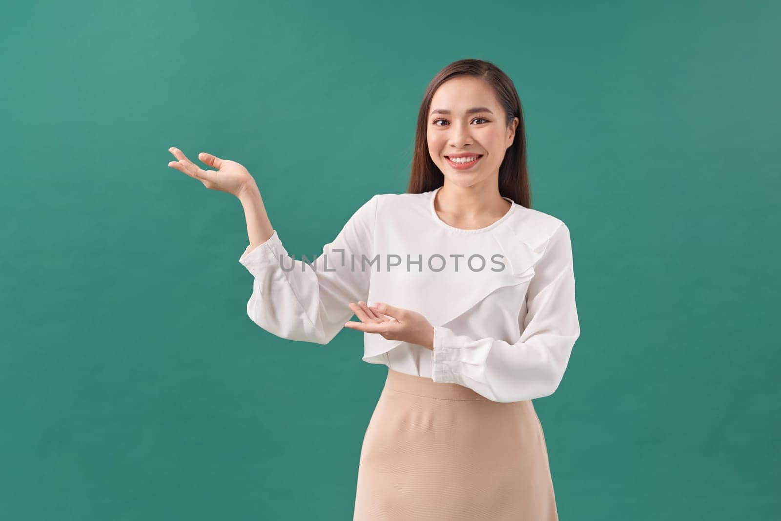 smiling beautiful young woman showing copyspace over green background