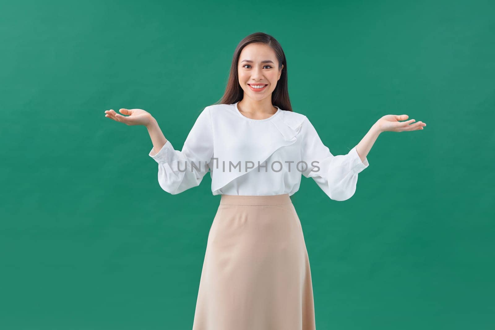 smiling beautiful young woman showing copyspace over green background