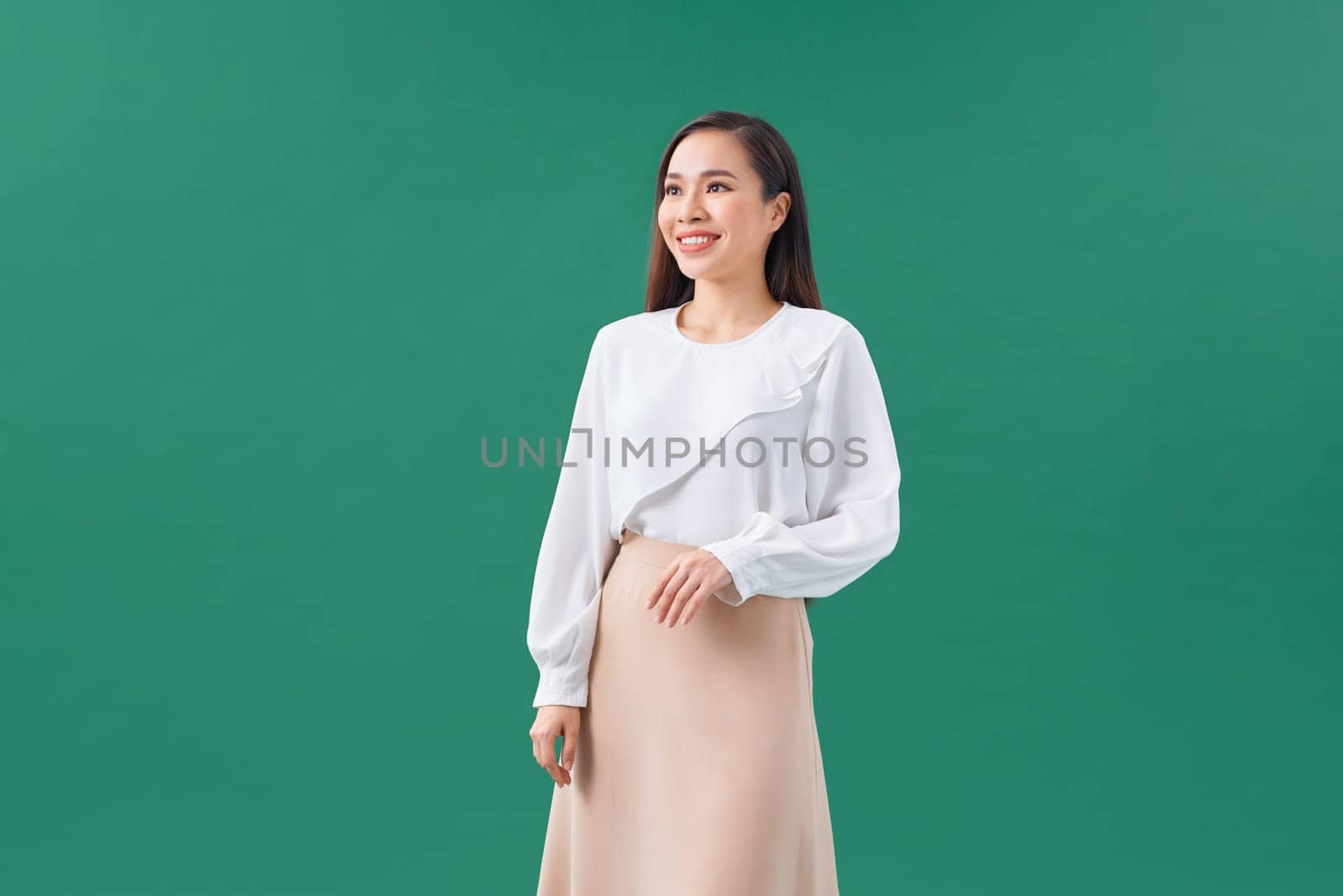 Smiling, beautiful asian woman posing on a green wall.