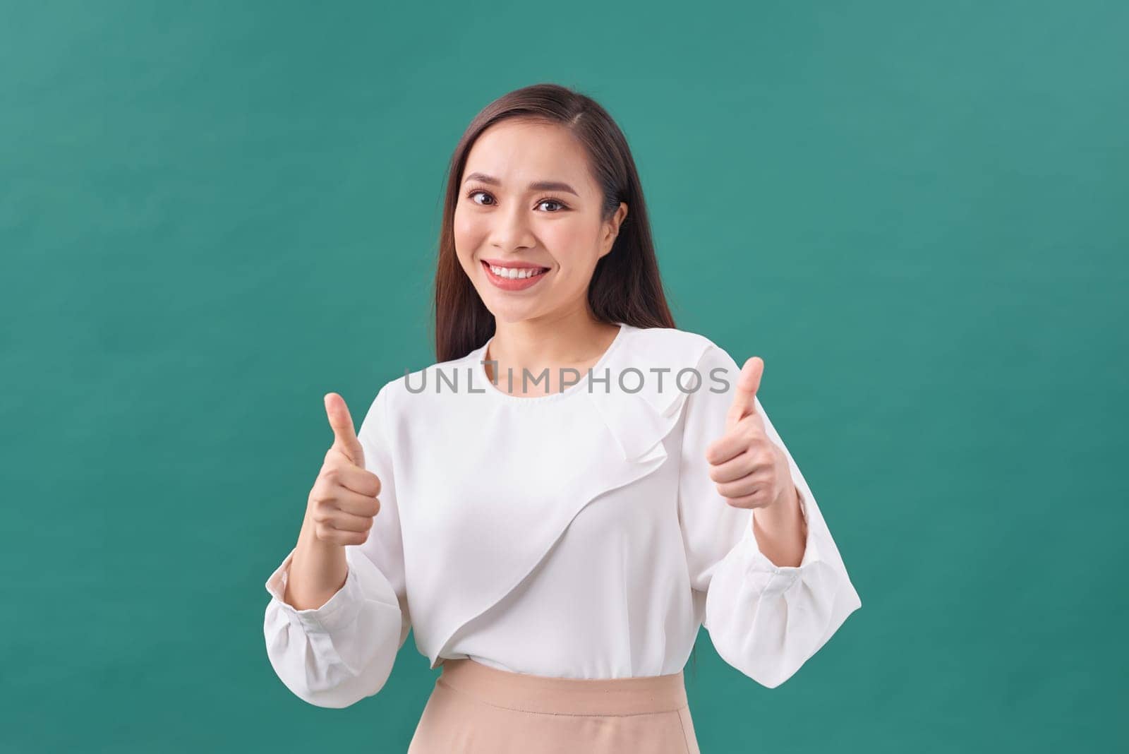 Smiling pretty young woman showing thumbs up isolated on the green background