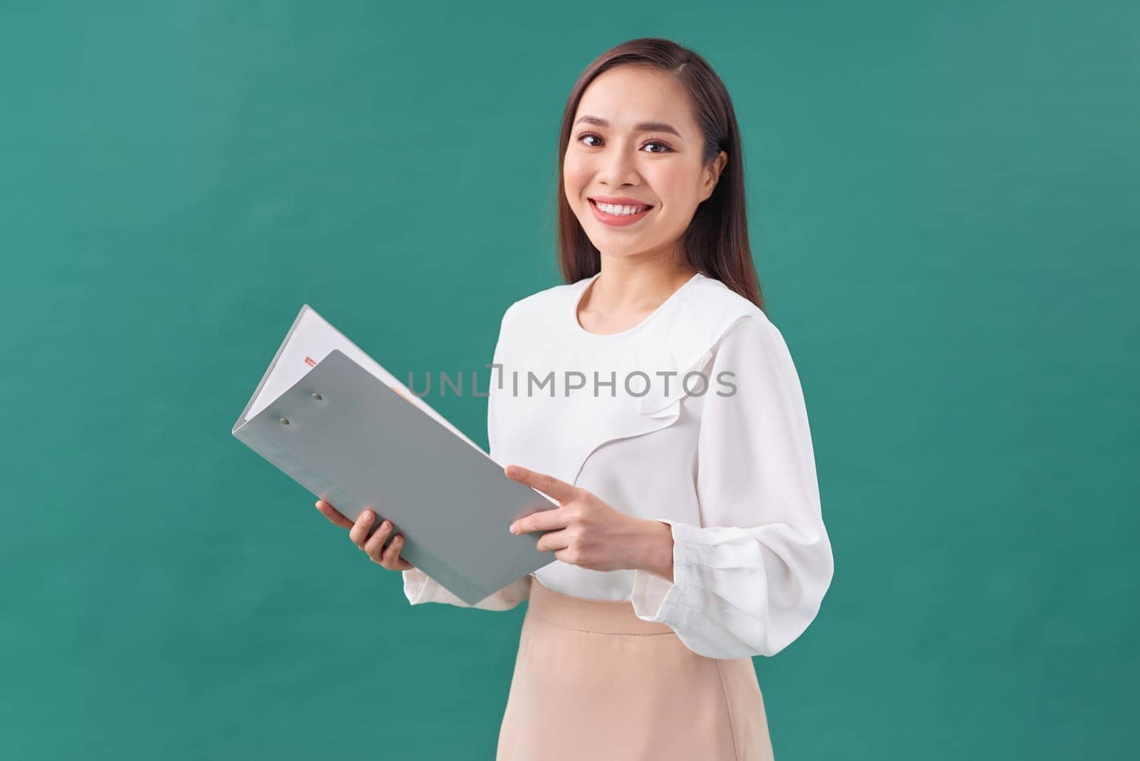 Portrait of a happy asian businesswoman holding clipboard isolated over green background