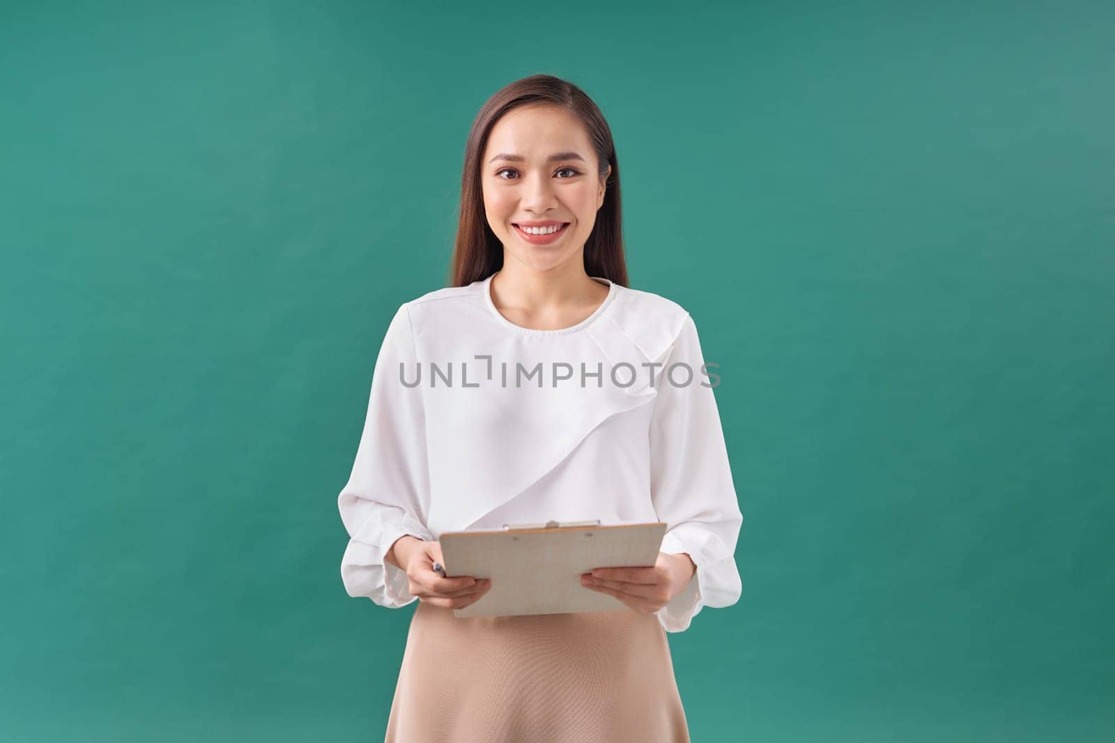 Beautiful business woman taking notes on her clipboard isolated on green background