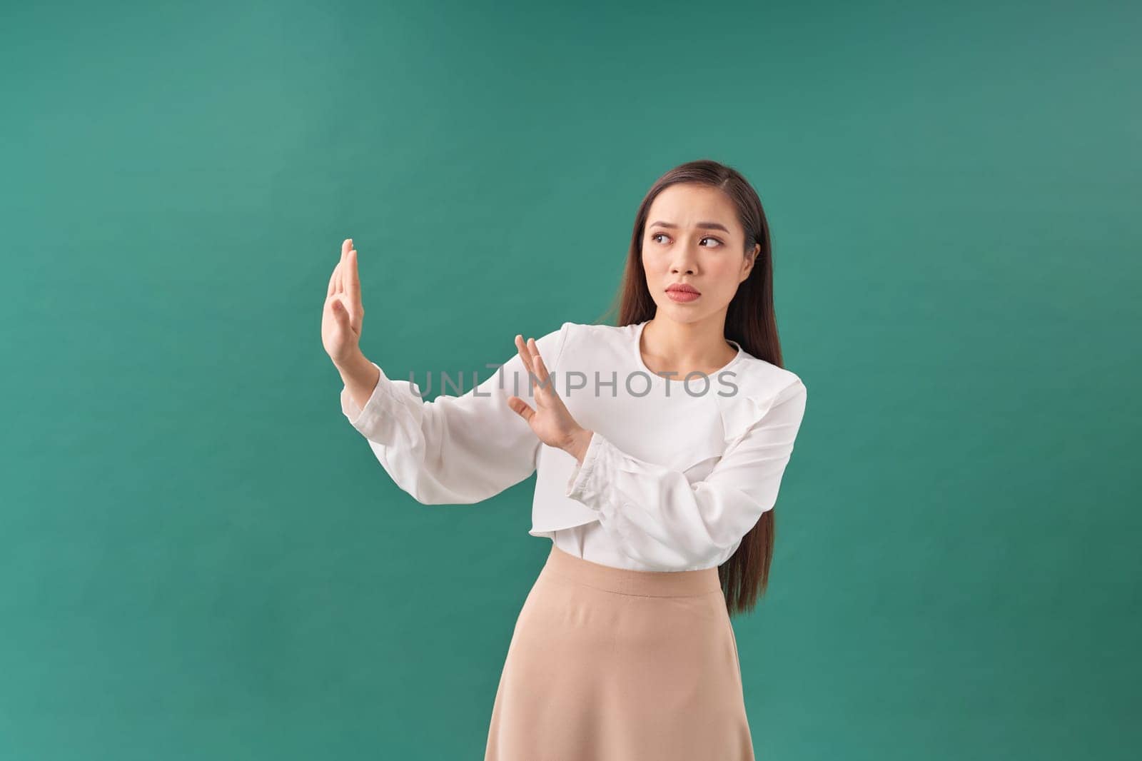 Asian woman in a casual suit saying no to her side with an open palm gesture.  by makidotvn