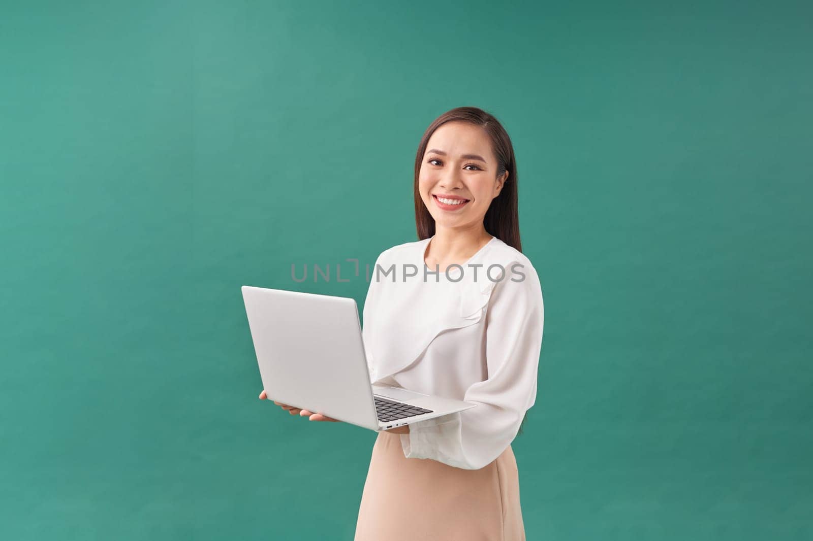 Young happy smiling woman in casual clothes holding laptop and sending email to her best friend