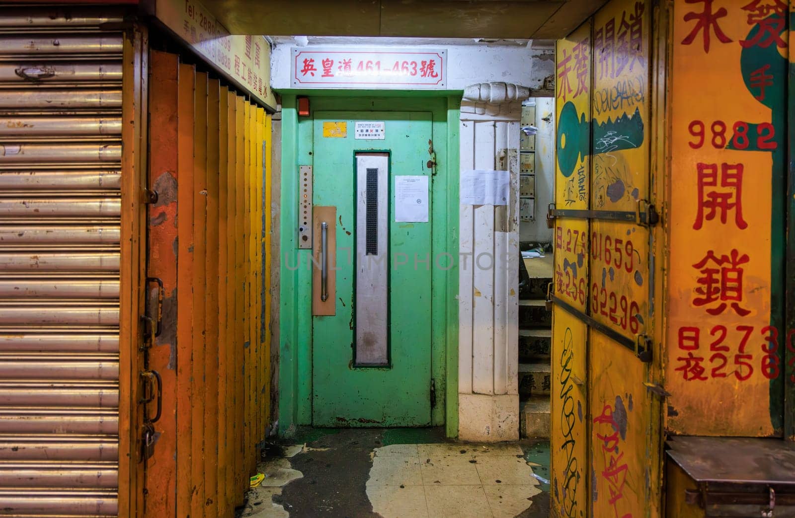 Dimly lit entrance door to old building with drawing and sign for key maker in Chinese. High quality photo