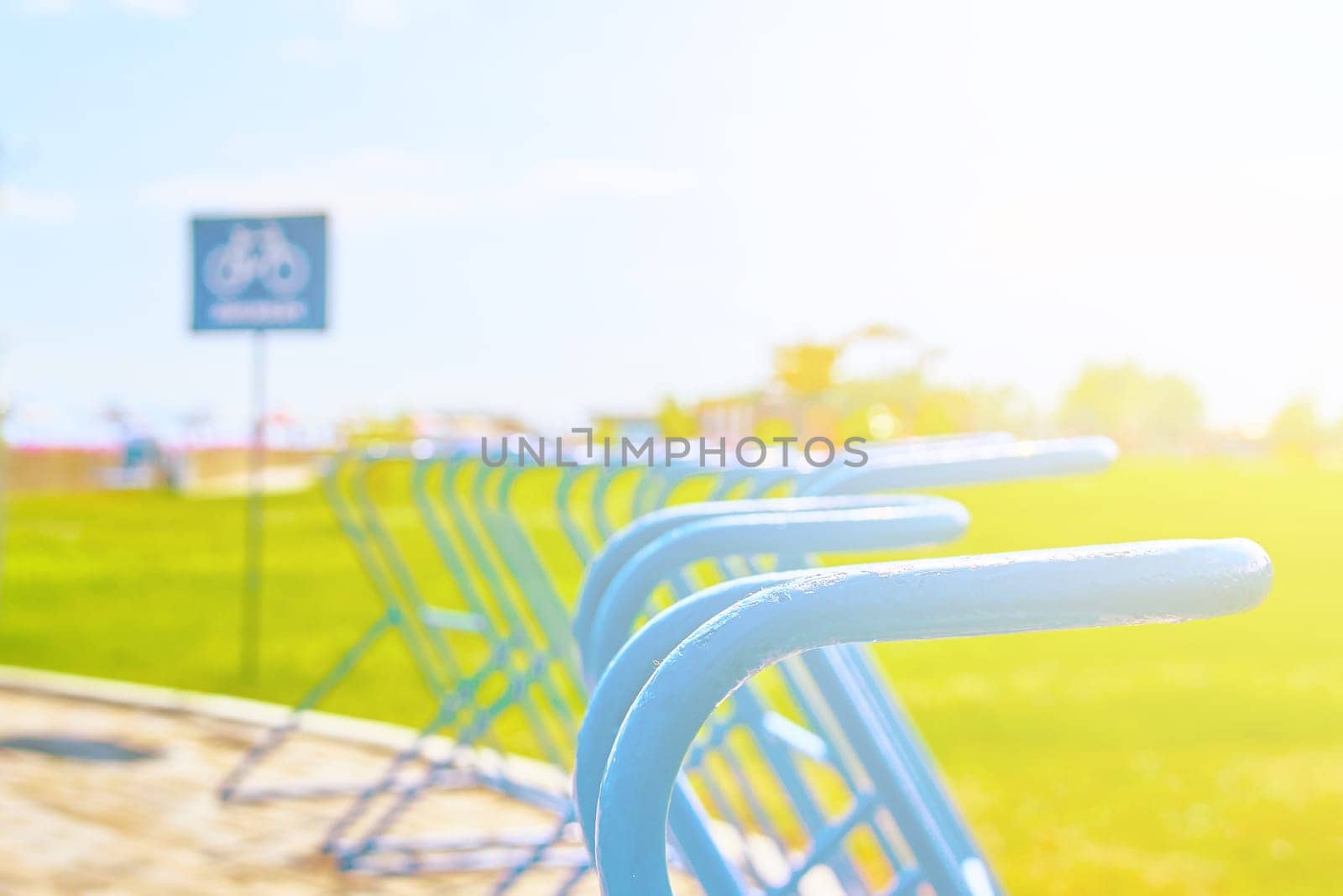 Bikes Parking free spaces on the ocean front against sunset and beach umbrellas and sign behind