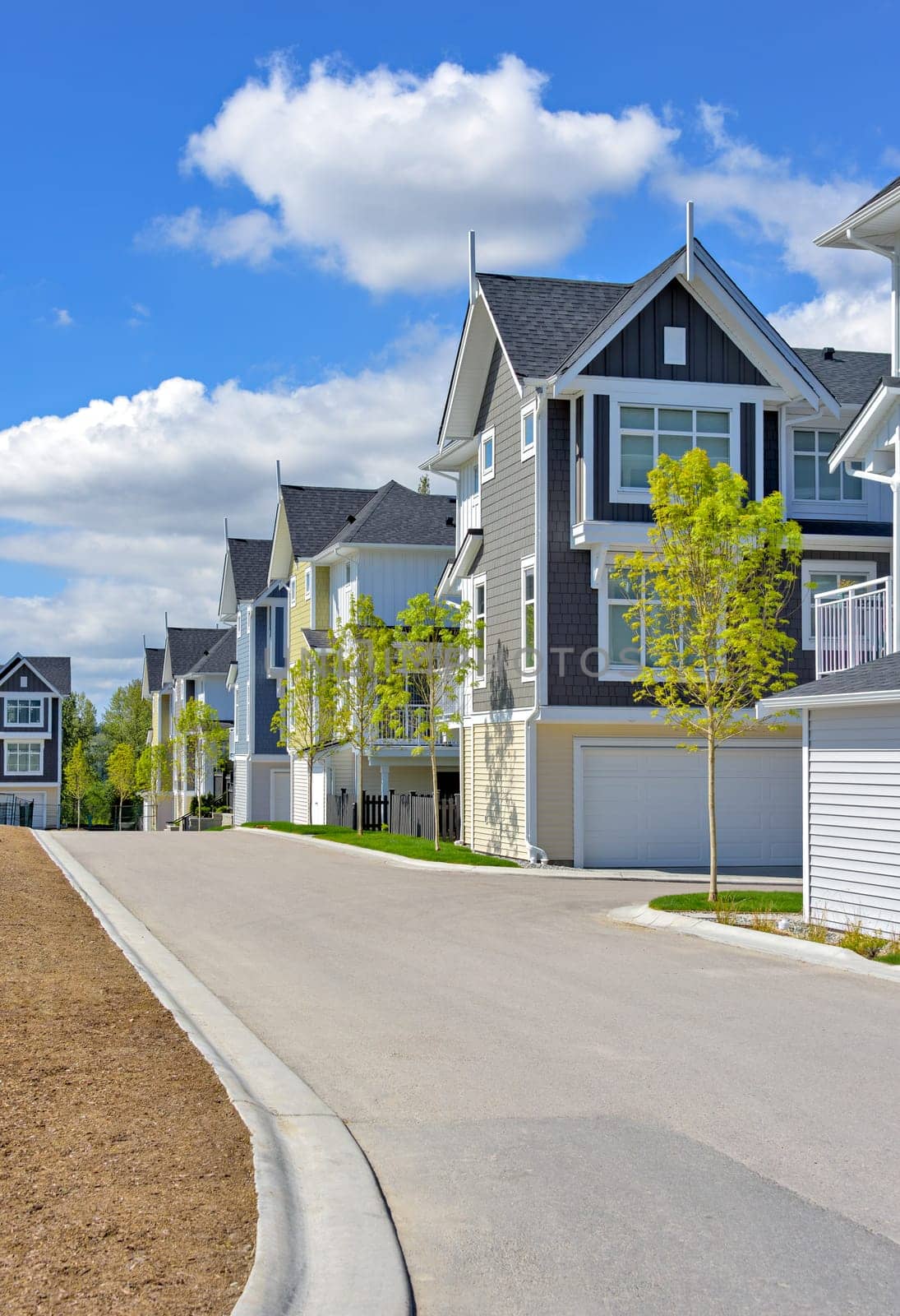 A perfect neighborhood. Brand new townhouses district on blue sky and clouds background.