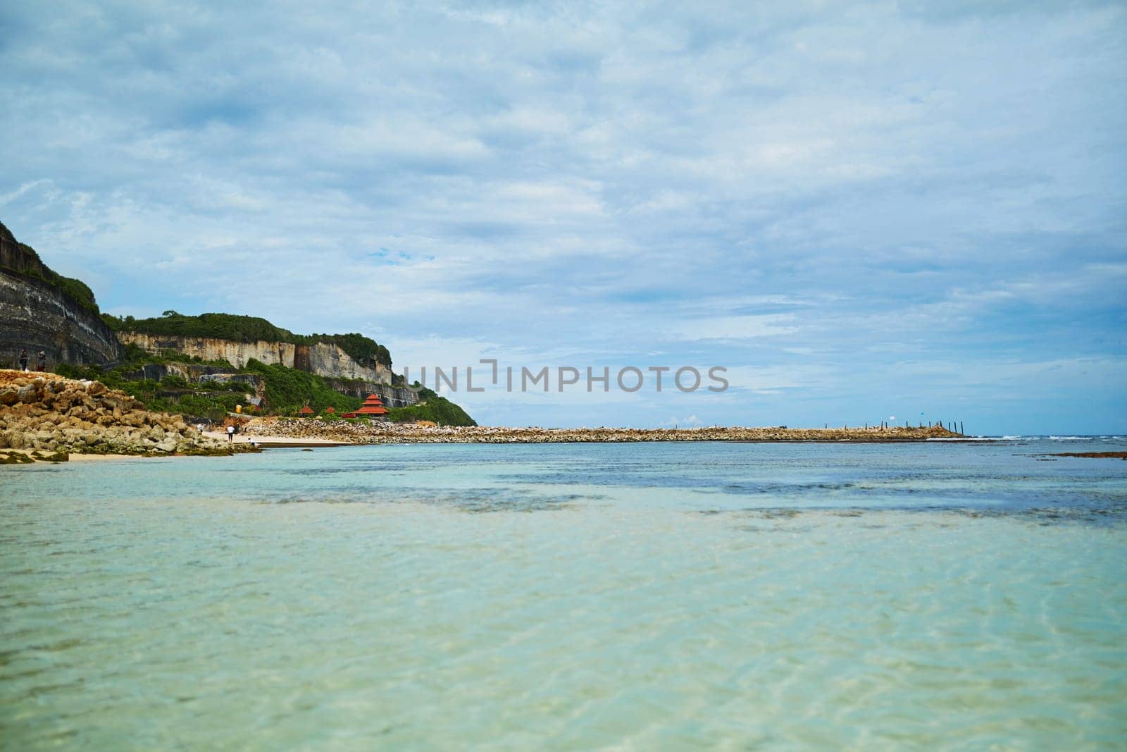 An incredibly beautiful deserted tropical beach under a cliff with clear, clean ocean water on the popular tourist island of Bali
