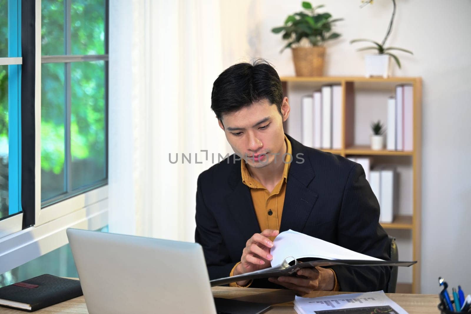 Serious male entrepreneur checking reports and preparing a presentation at workspace.