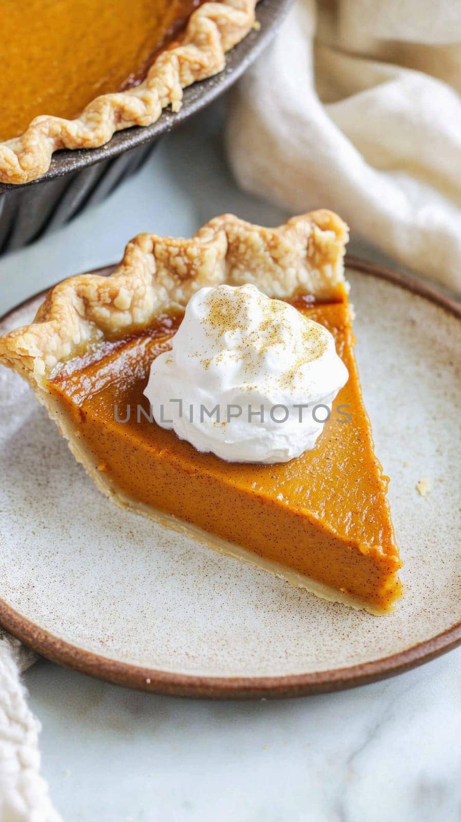 Delicious slice of pumpkin pie topped with whipped cream and a sprinkle of cinnamon, sitting on a rustic plate