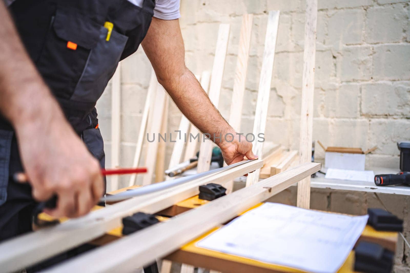 Unrecognizable men measuring wooden plank outdoors.