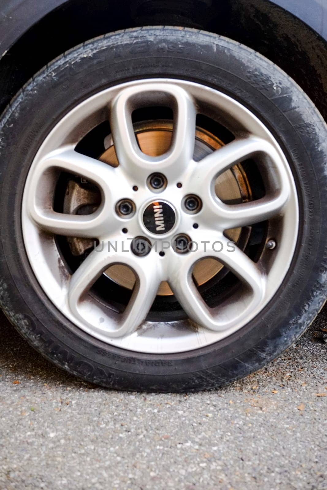 Cremona, Itally - October 6th 2024 Close-up of a dirty silver alloy wheel and tire on a mini cooper s r56 parked on asphalt. Showcasing intricate details and contrasting colors