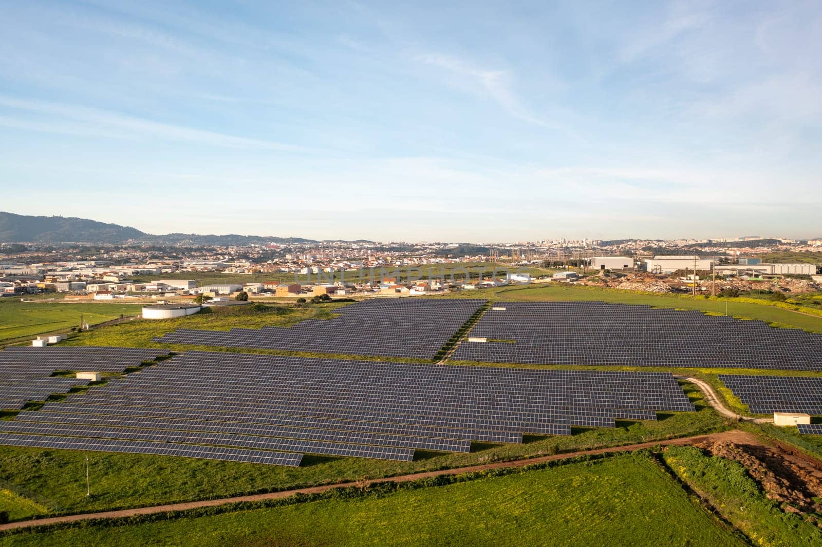 Aerial drone view of solar panels on agricultural field during sunny day. The landscape is fully equipped with green renewable energy generators.