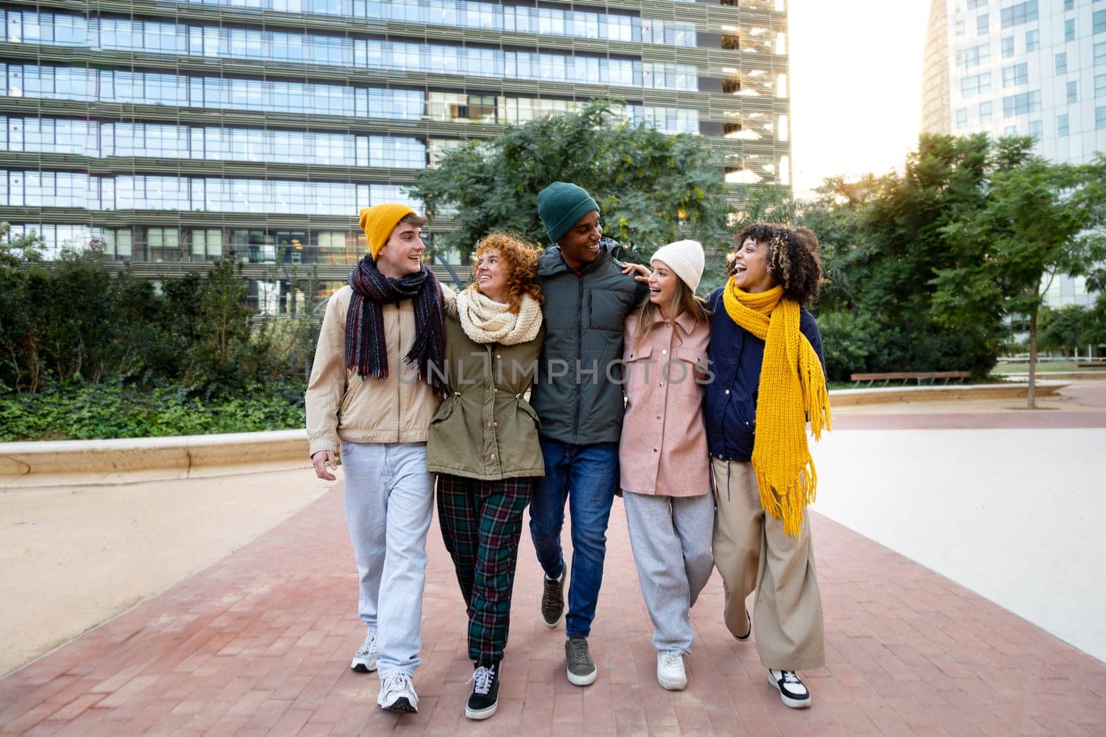 Group of happy multiracial friends embracing together walking around city in a winter day. Friendship and lifestyle concept.
