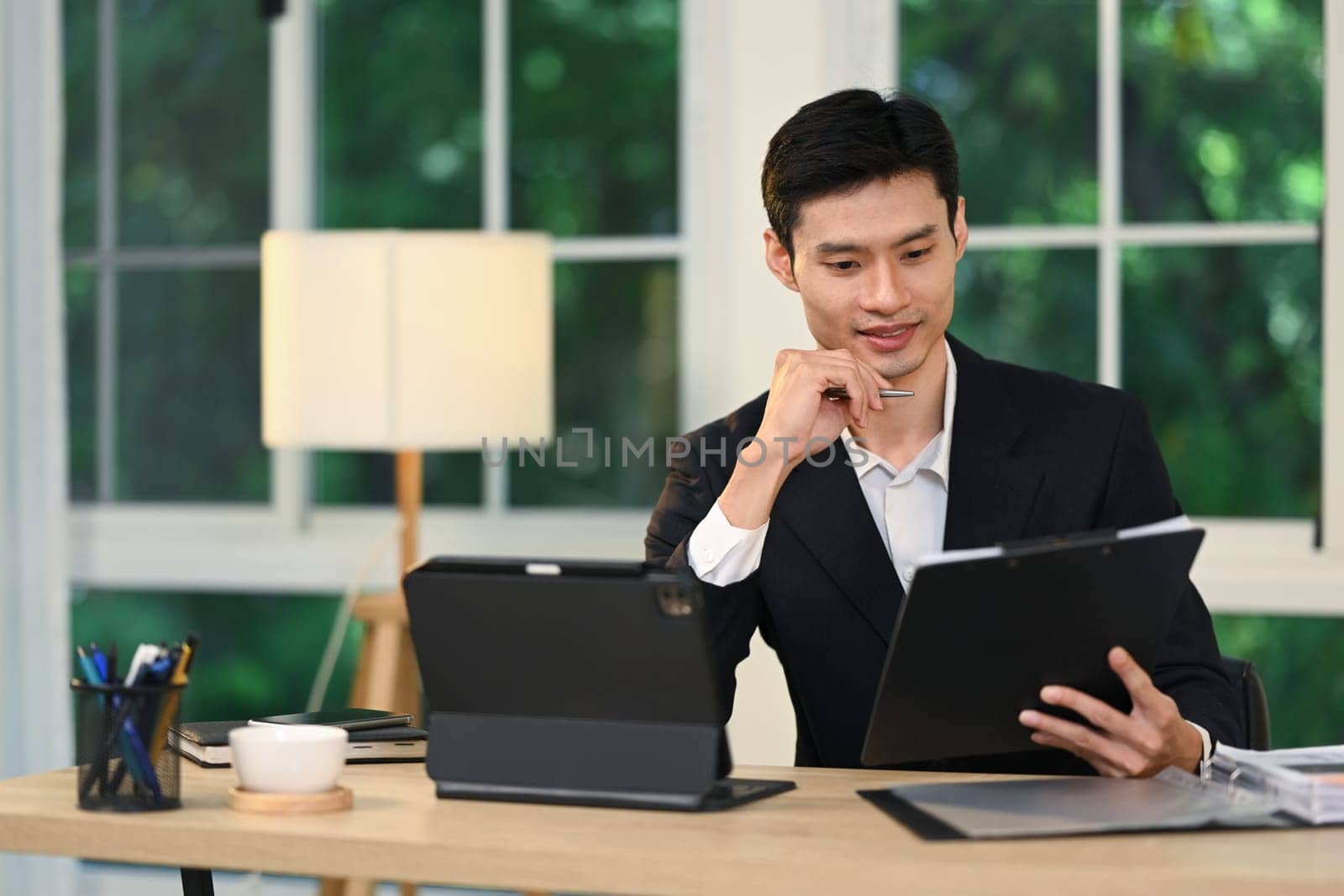 Businessman in elegant suit working with digital tablet in modern office.