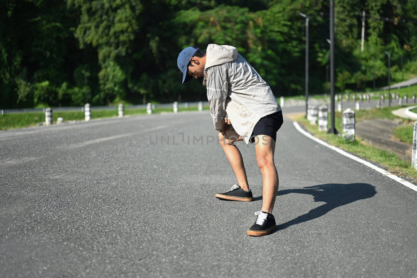 Athlete man stretching outdoors preparing for run in nature.