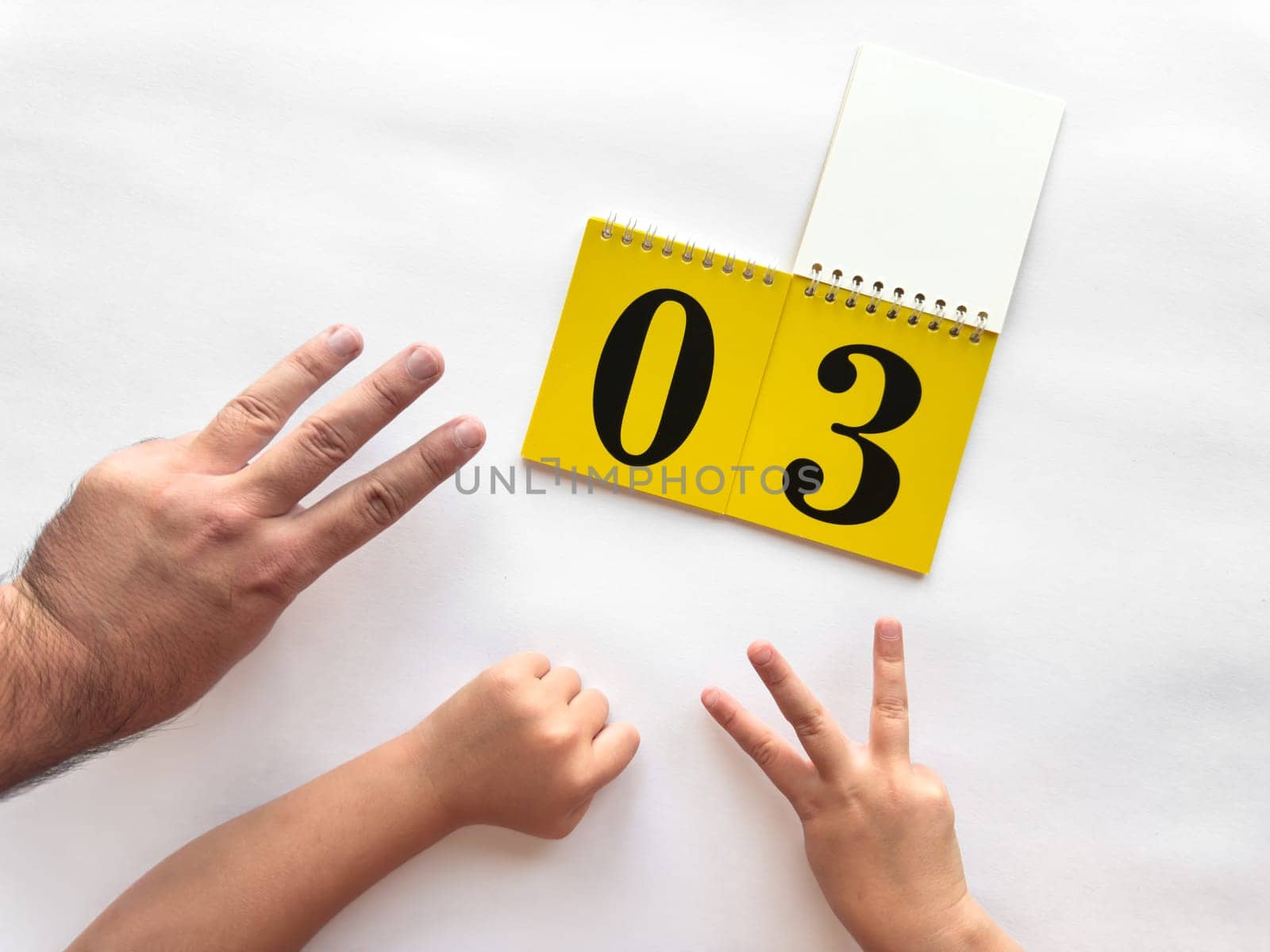 Counting hands with yellow calendar displaying number three for learning.