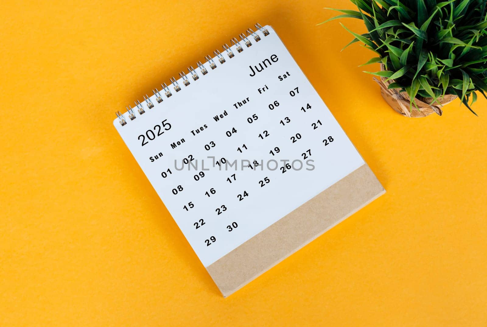 June 2025 desk calendar on yellow background. Directly above. Flat lay. Copy space.