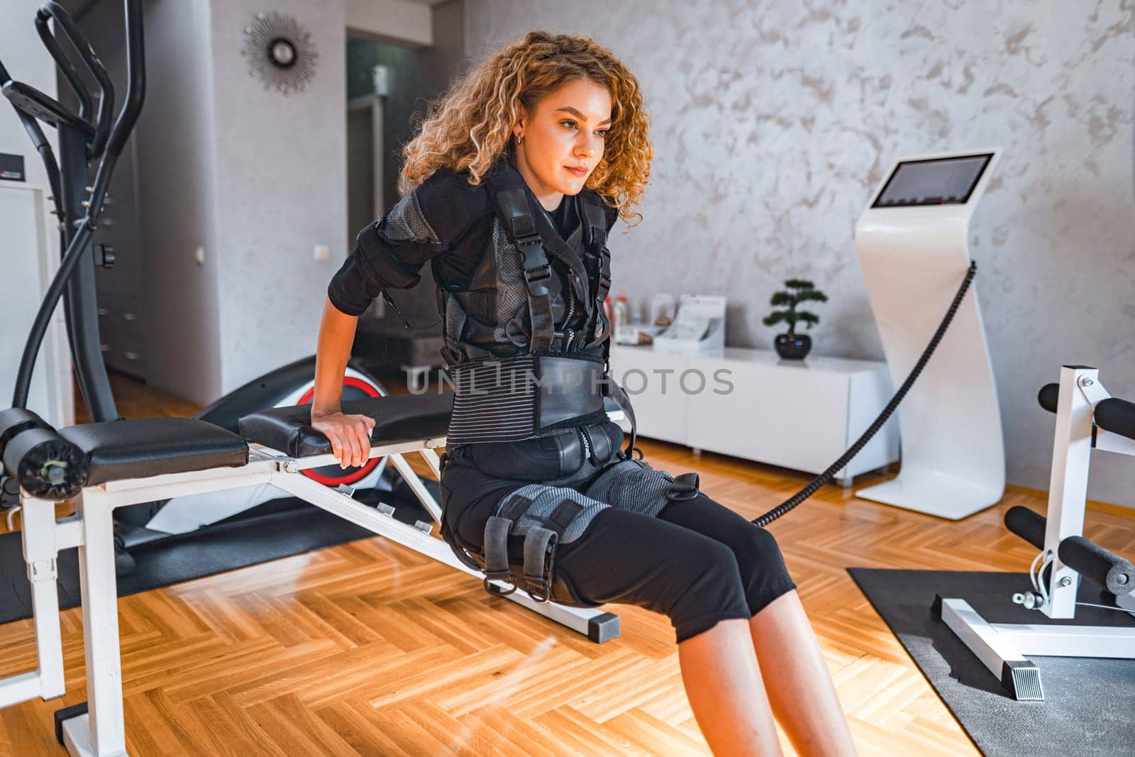 A woman in sleek workout attire performs a body toning exercise indoors.