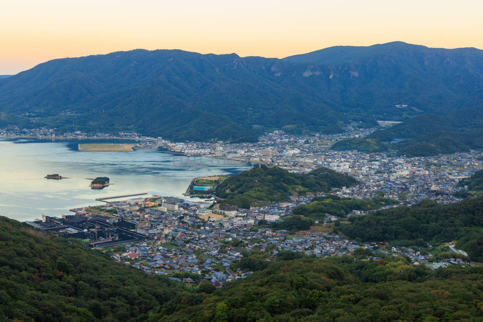 Small coastal town by green forested mountains on Shodo Island at dawn by Osaze