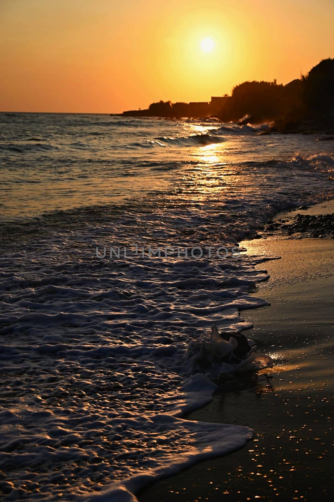 Beautiful sunset on the beach with the sea. Waves on the sea. Greece - Corfu island (Kerkyra) Agios Georgios. A concept for travel, holidays and summer vacations. 