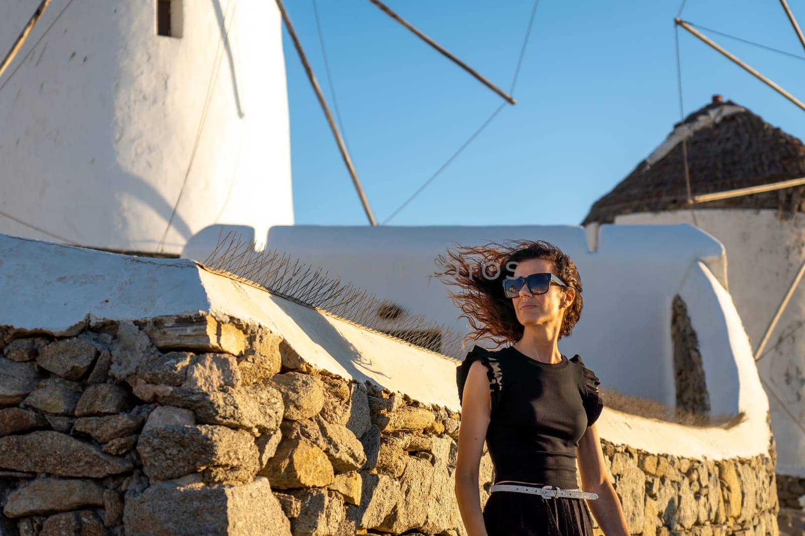 Young woman in black dress at the windmills in Mykonos