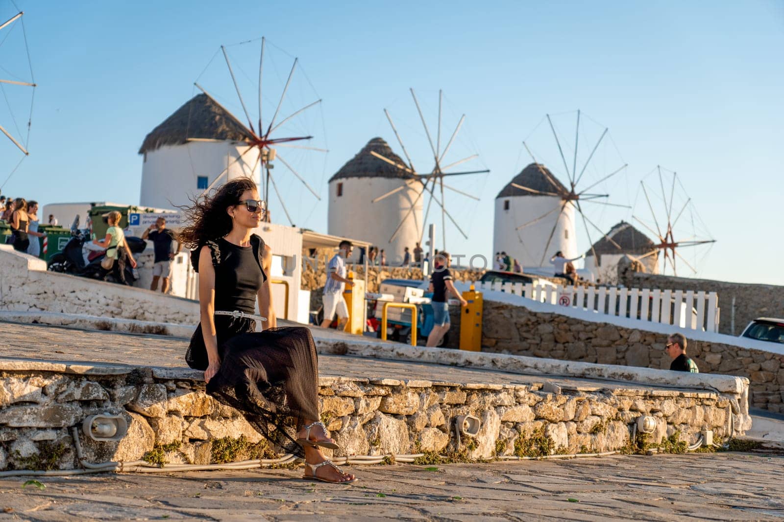 Young woman in black dress at the windmills in Mykonos