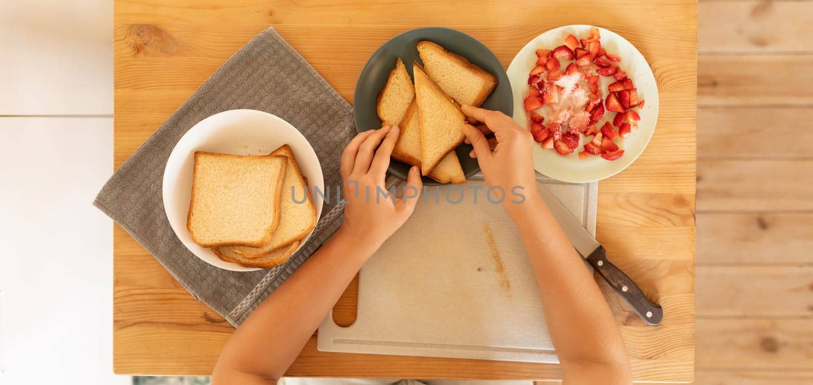 Top view, a woman making cream cheese toast with strawberries for a snack.
