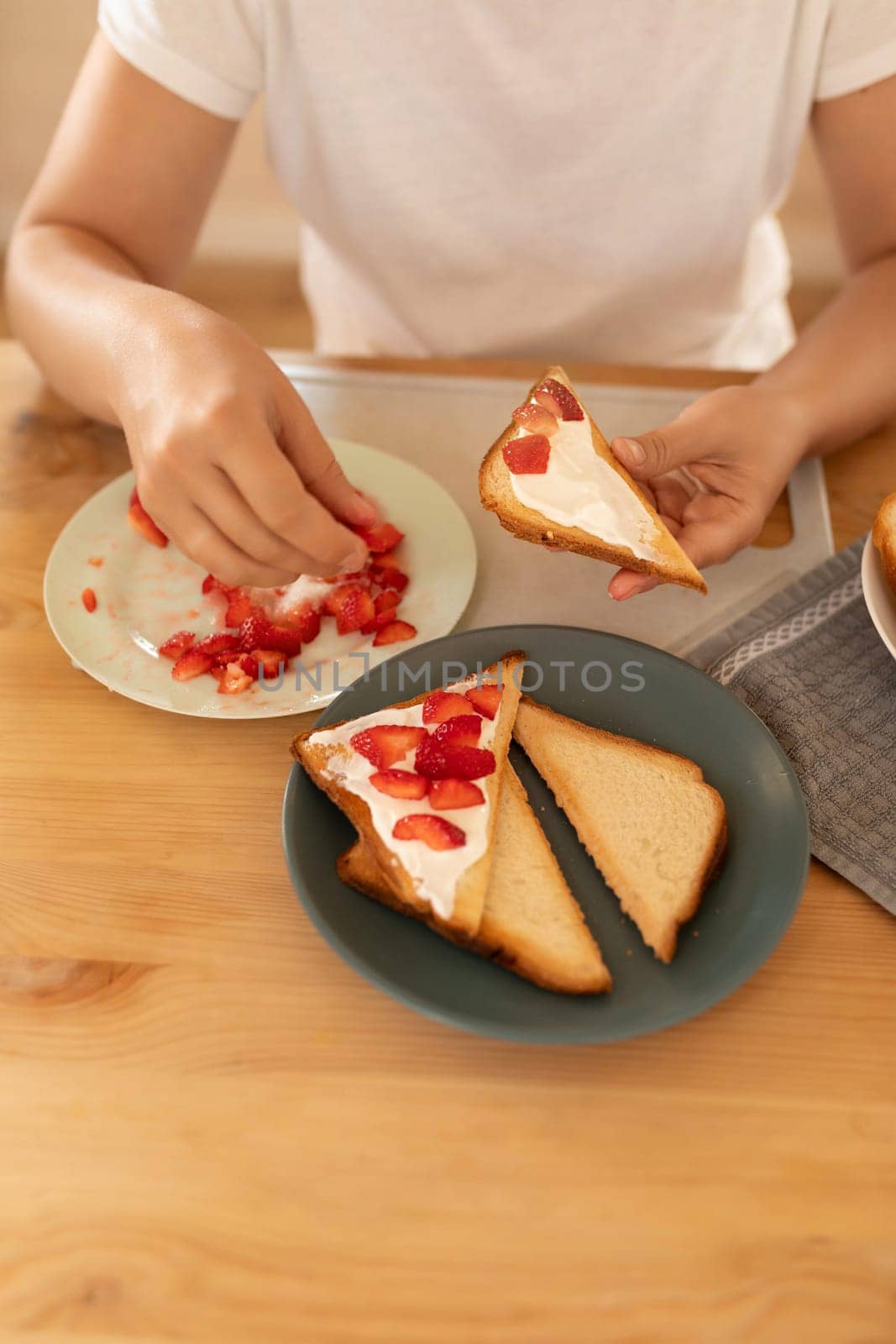 a woman makes breakfast, toast with sour cream and strawberries.