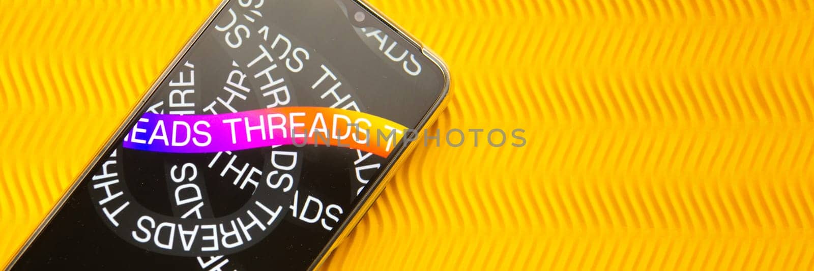 Tver, Russia - July 15, 2023, threads logo on the smartphone screen, on a yellow background. The threads icon. The logo of the current application. Threads social network. by Annu1tochka