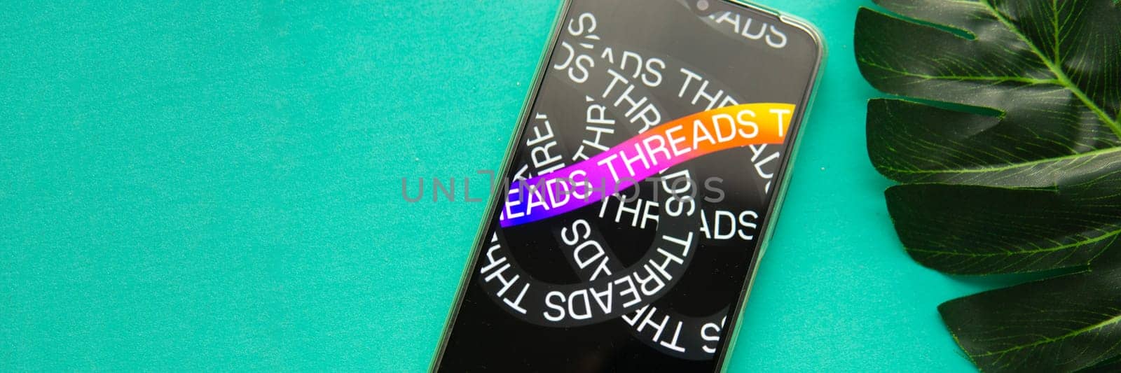 Tver, Russia - July 15, 2023, threads logo on the smartphone screen, on a green background. The threads icon. The logo of the current application. Threads social network