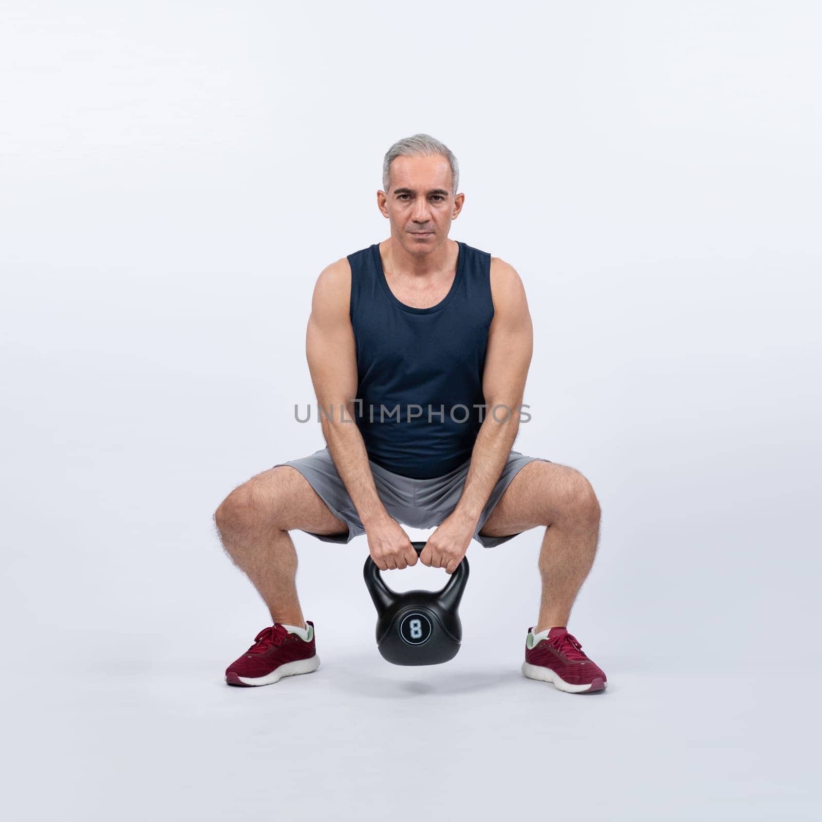 Full body length shot athletic senior man doing squat with weight. Clout by biancoblue