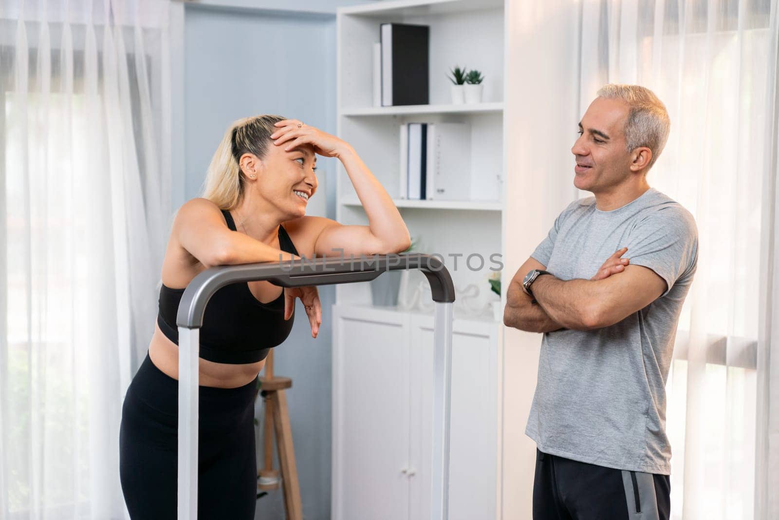 Active senior couple running on tread running machine at home together as fitness healthy lifestyle and body care after retirement for pensioner. Clout