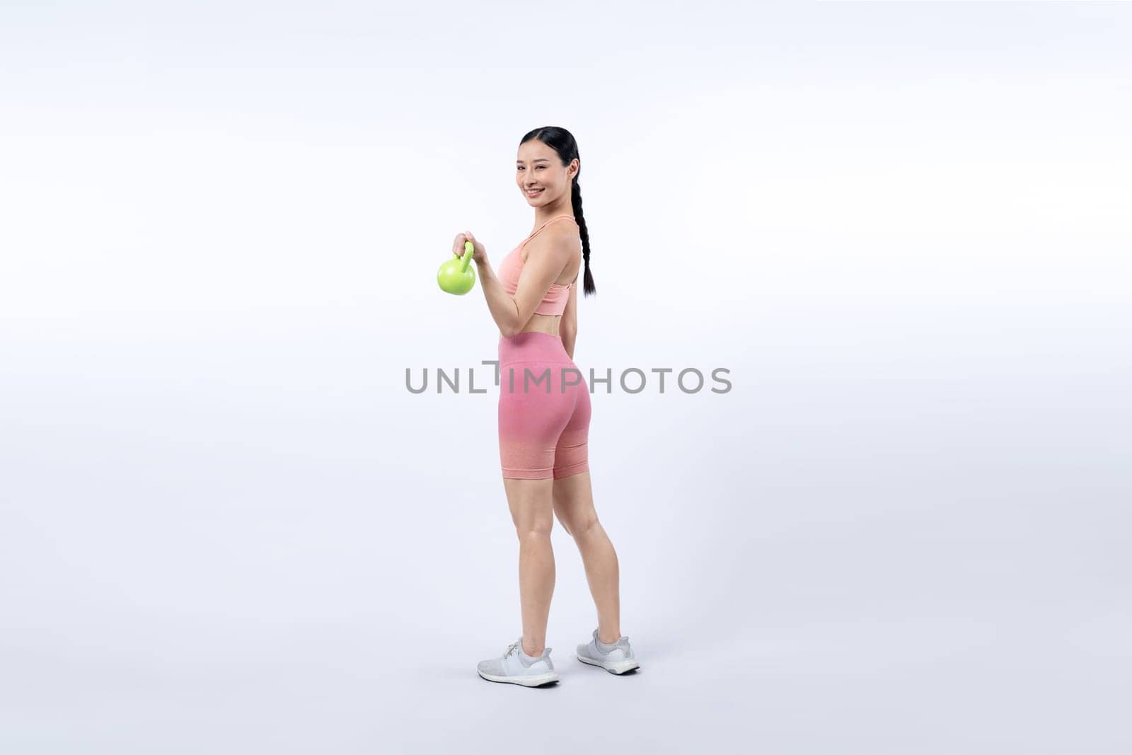 Vigorous energetic woman doing yoga with kettlebell weight exercise. by biancoblue