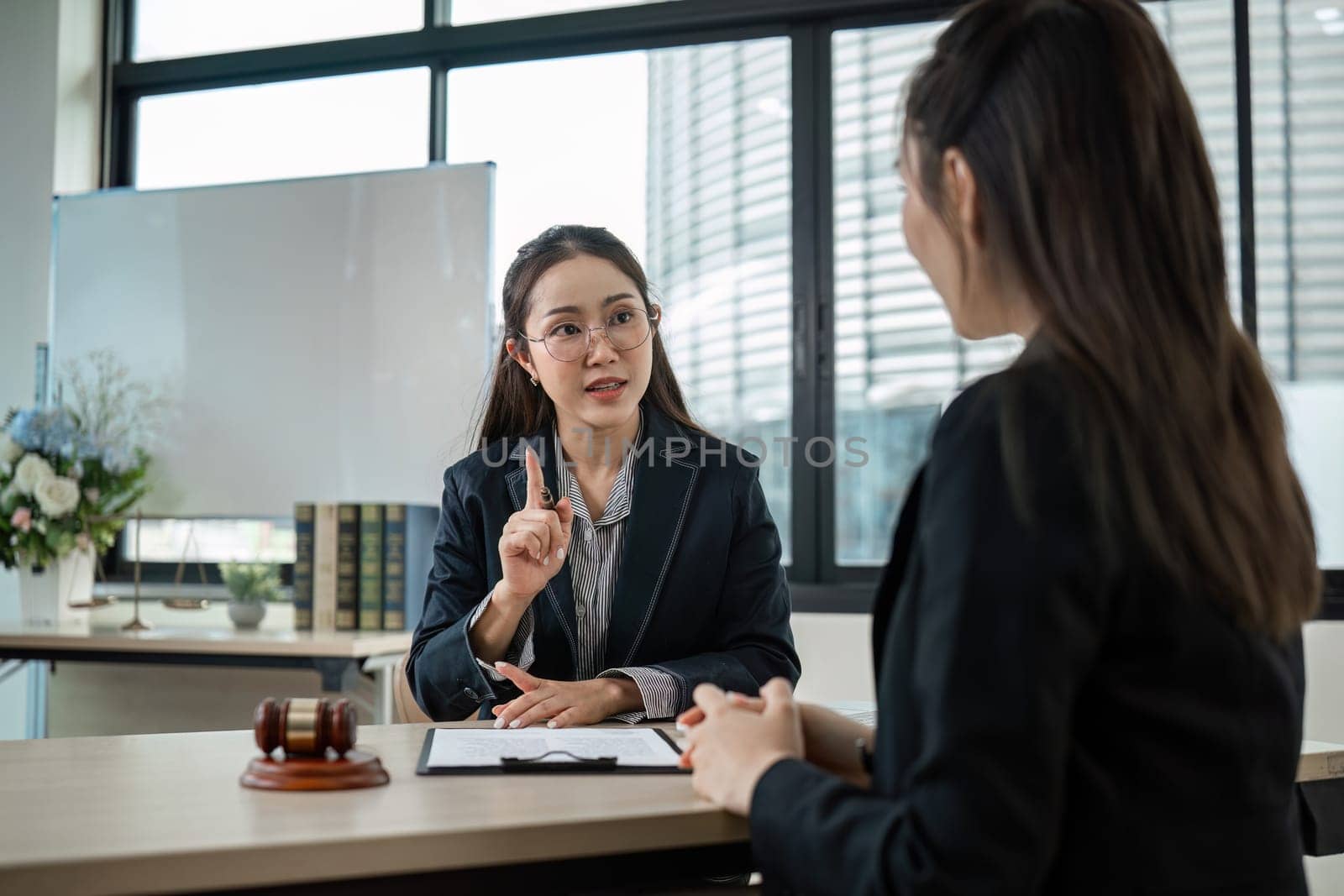 A young lawyer provides legal advice to a client in a modern office, showcasing professionalism and expertise.