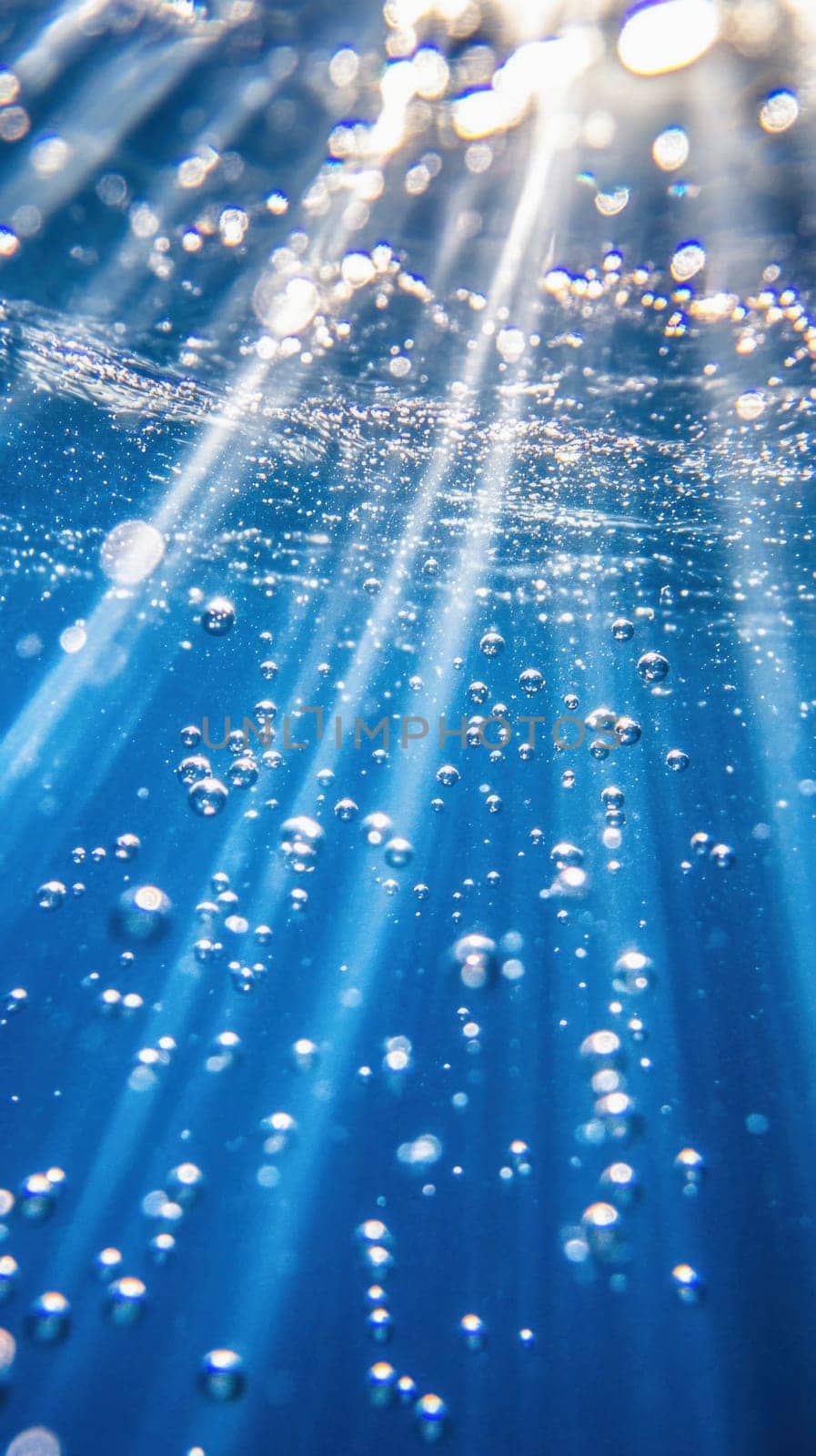 Beams of sunlight shining through crystal clear ocean water and creating beautiful light rays and air bubbles
