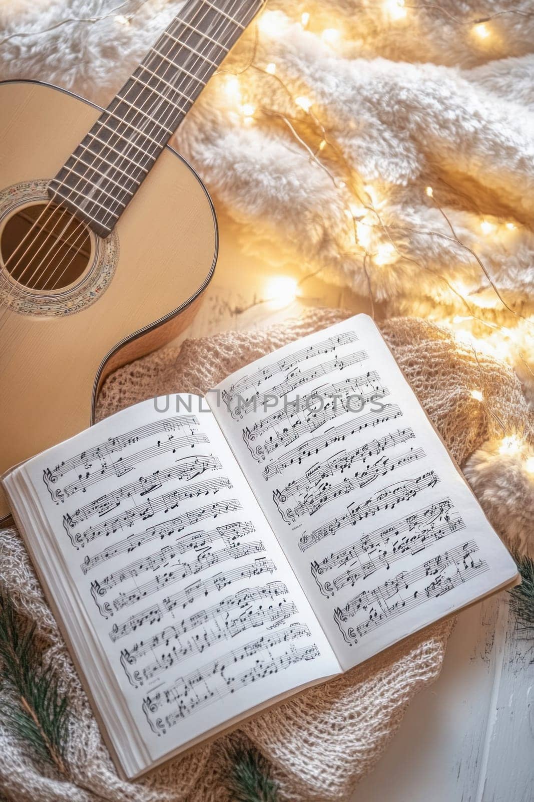 Acoustic guitar and sheet music rest on a soft blanket, adorned with warm fairy lights, evoking a cozy and musical ambiance