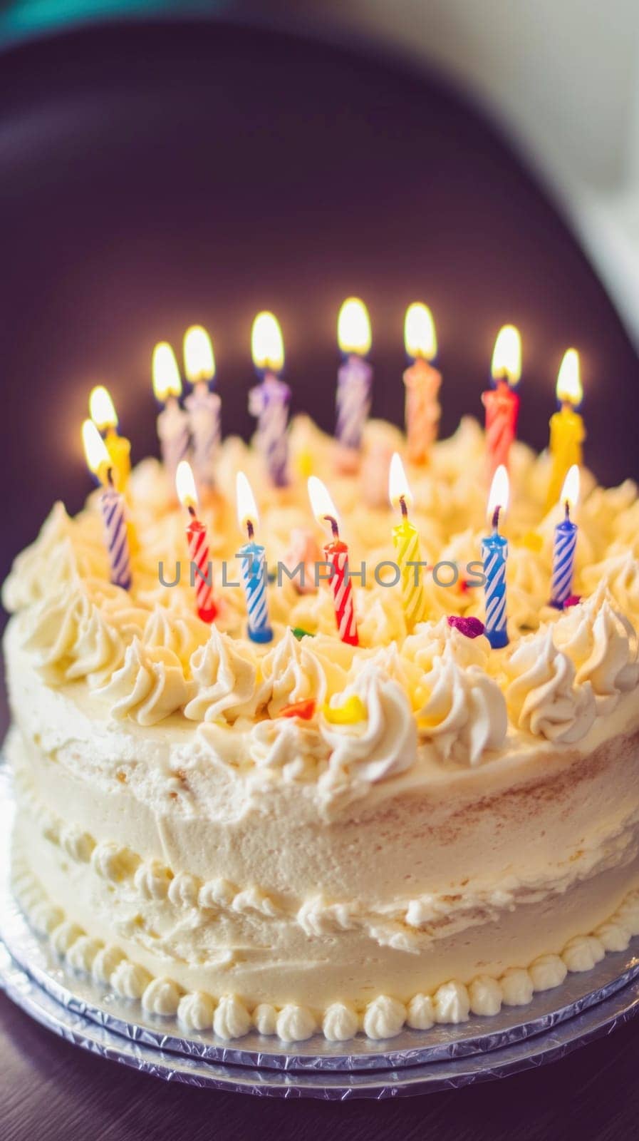 White frosted birthday cake with colorful lit candles, celebrating a special occasion