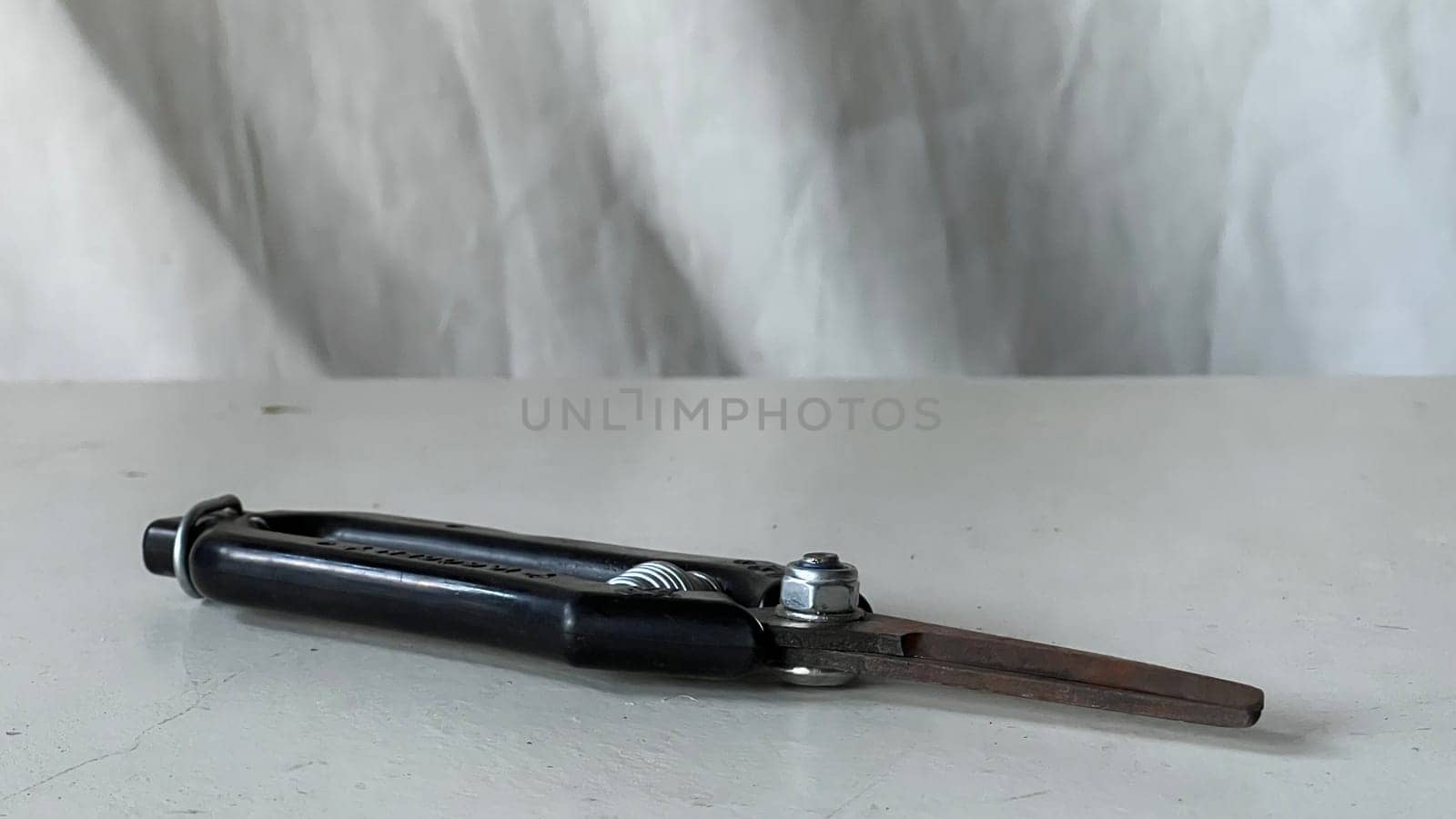 A metal compass is placed on a white surface, highlighting its design and functionality.