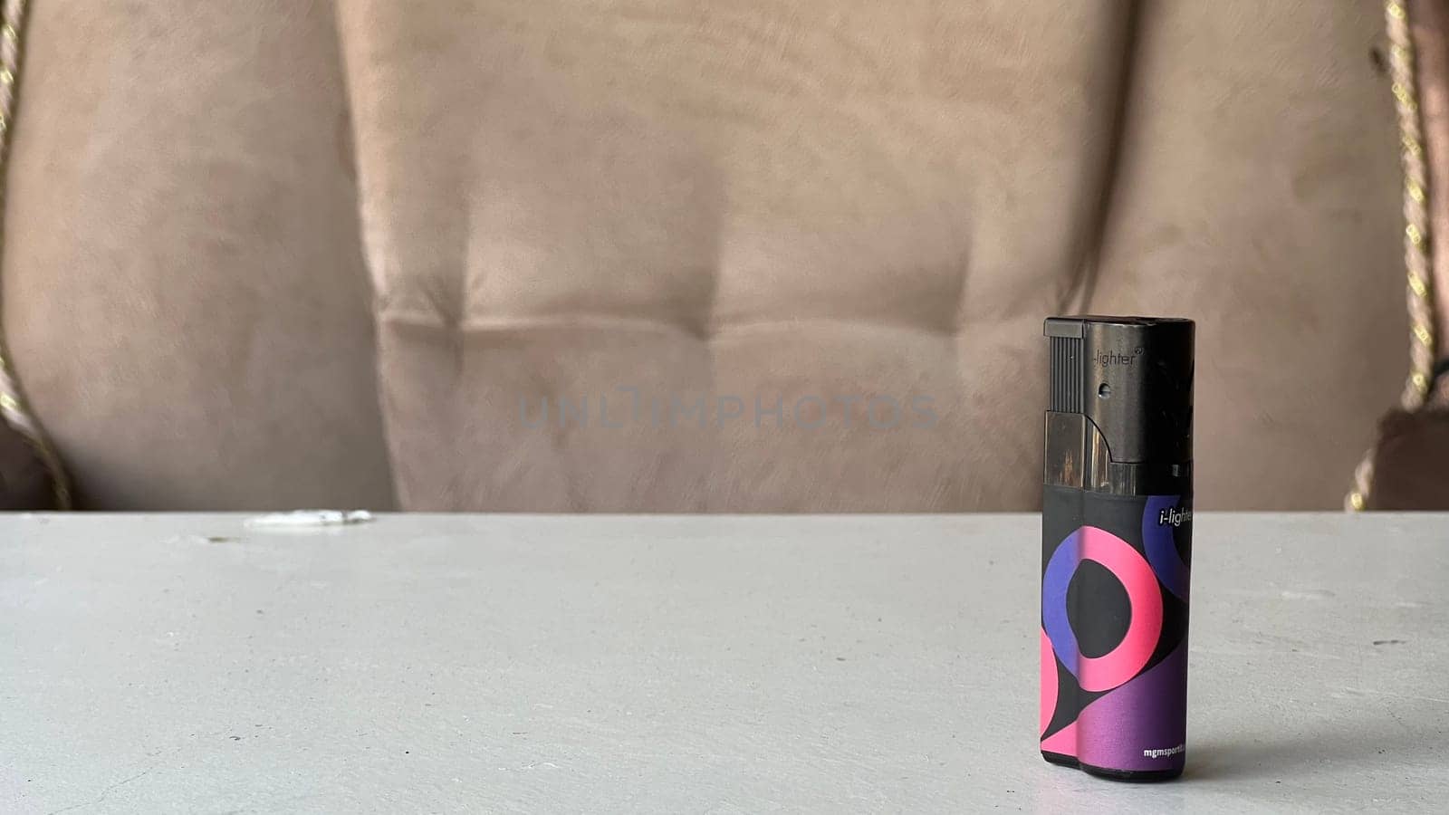 A compact vape device rests on a table with a soft couch in the background.