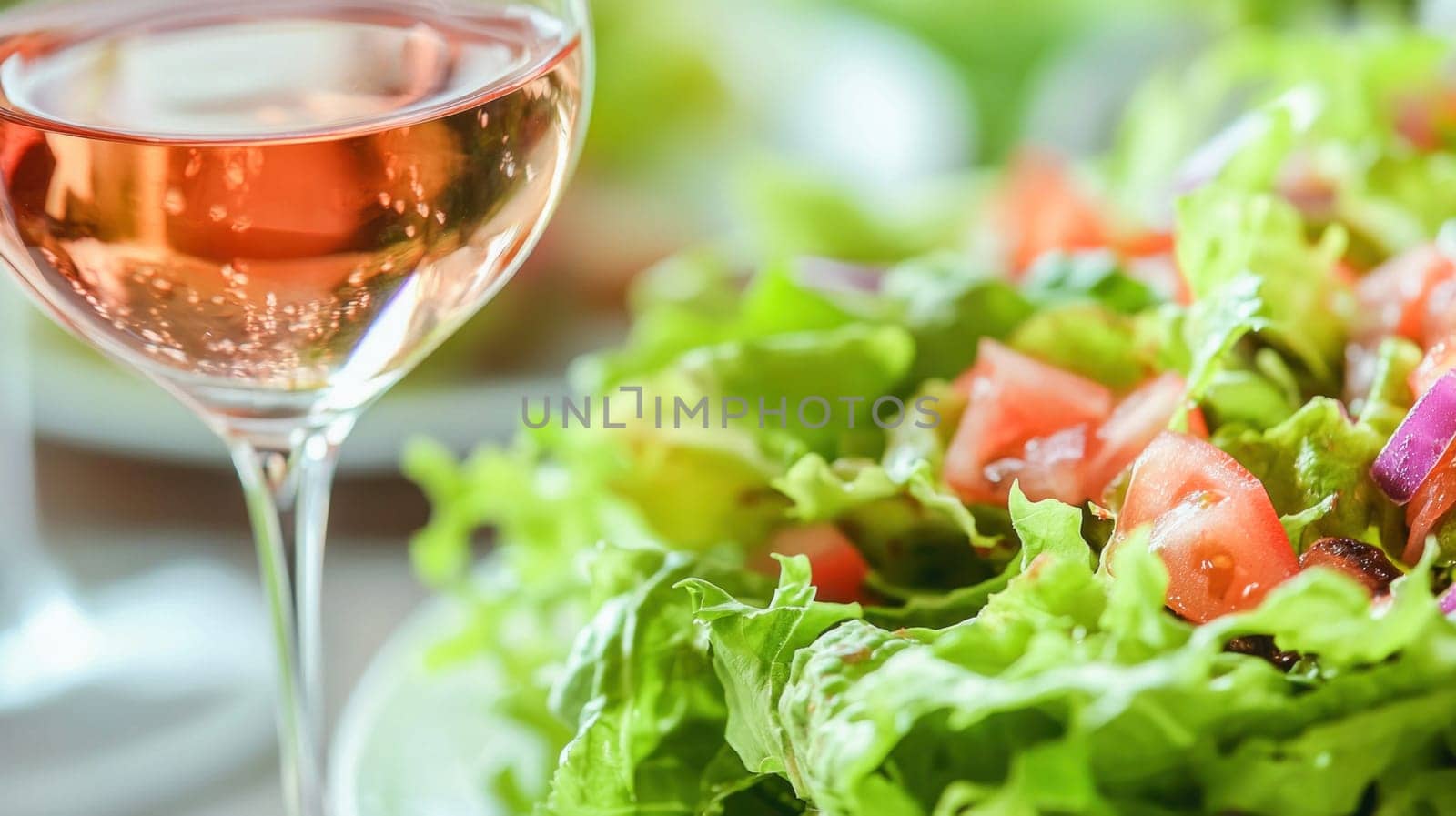 Rose wine enhances a healthy meal of fresh salad with lettuce, tomatoes and onions