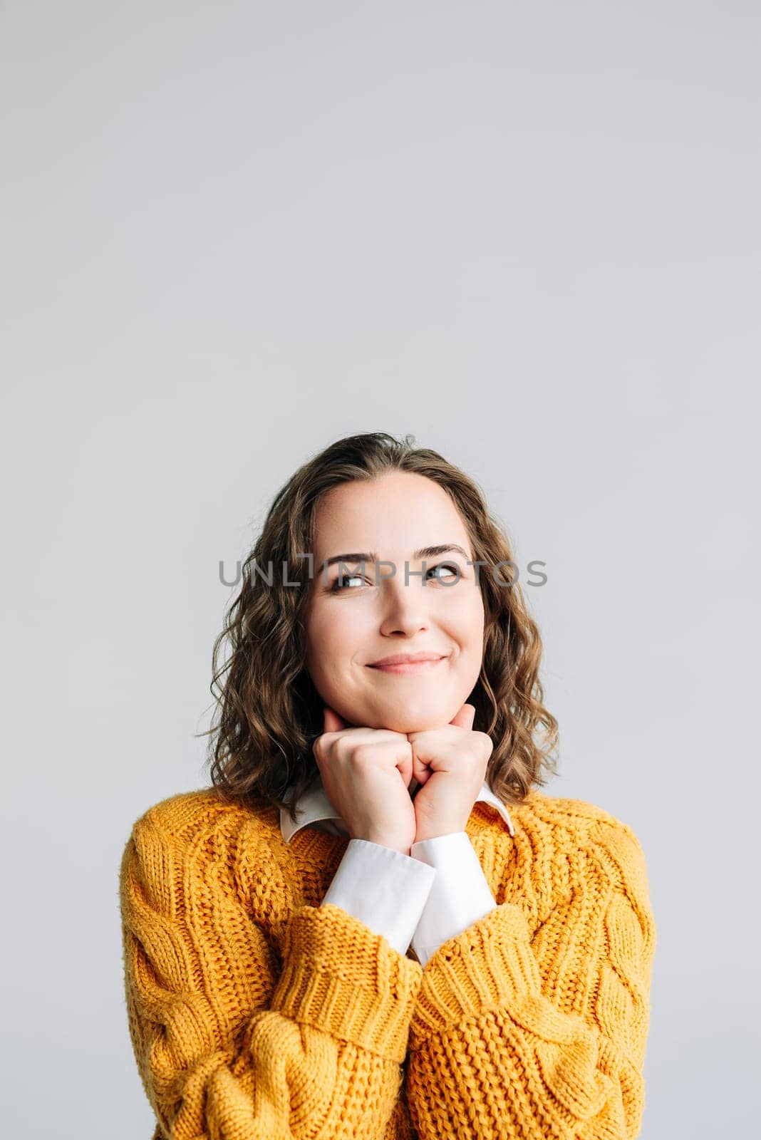 Young woman with a dreamy smile, hands resting on her chin, looking away thoughtfully. Captures a moment of contemplation and positivity. Isolated on a white background, perfect for lifestyle