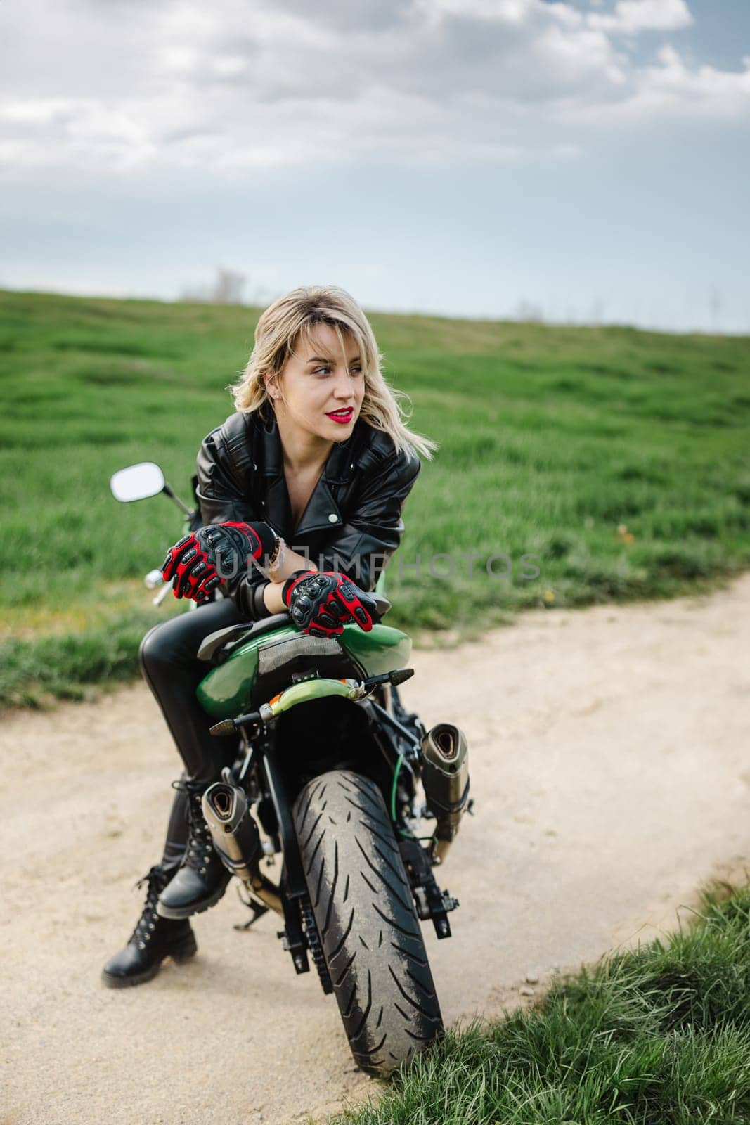 Woman in Leather Outfit Sitting on Motorcycle. Confident woman in leather pants and jacket sitting on a motorcycle. Ideal for themes of adventure, fashion, or biker lifestyle. Captures a bold.