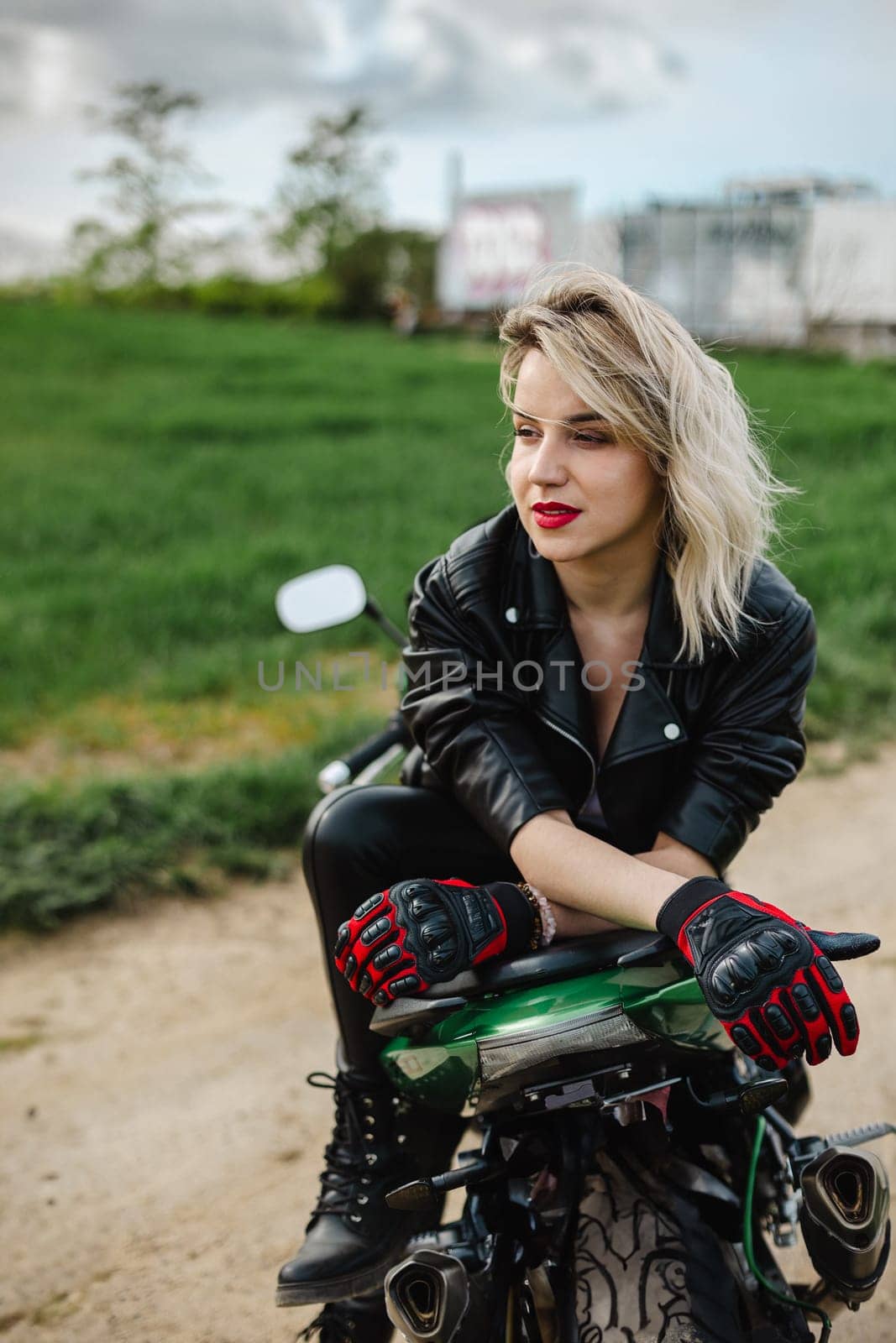 Woman in Black Leather Jacket on Motorcycle Outdoors. Stylish woman wearing a black leather jacket and gloves sits confidently on a motorcycle in an outdoor setting, capturing a sense of freedom.
