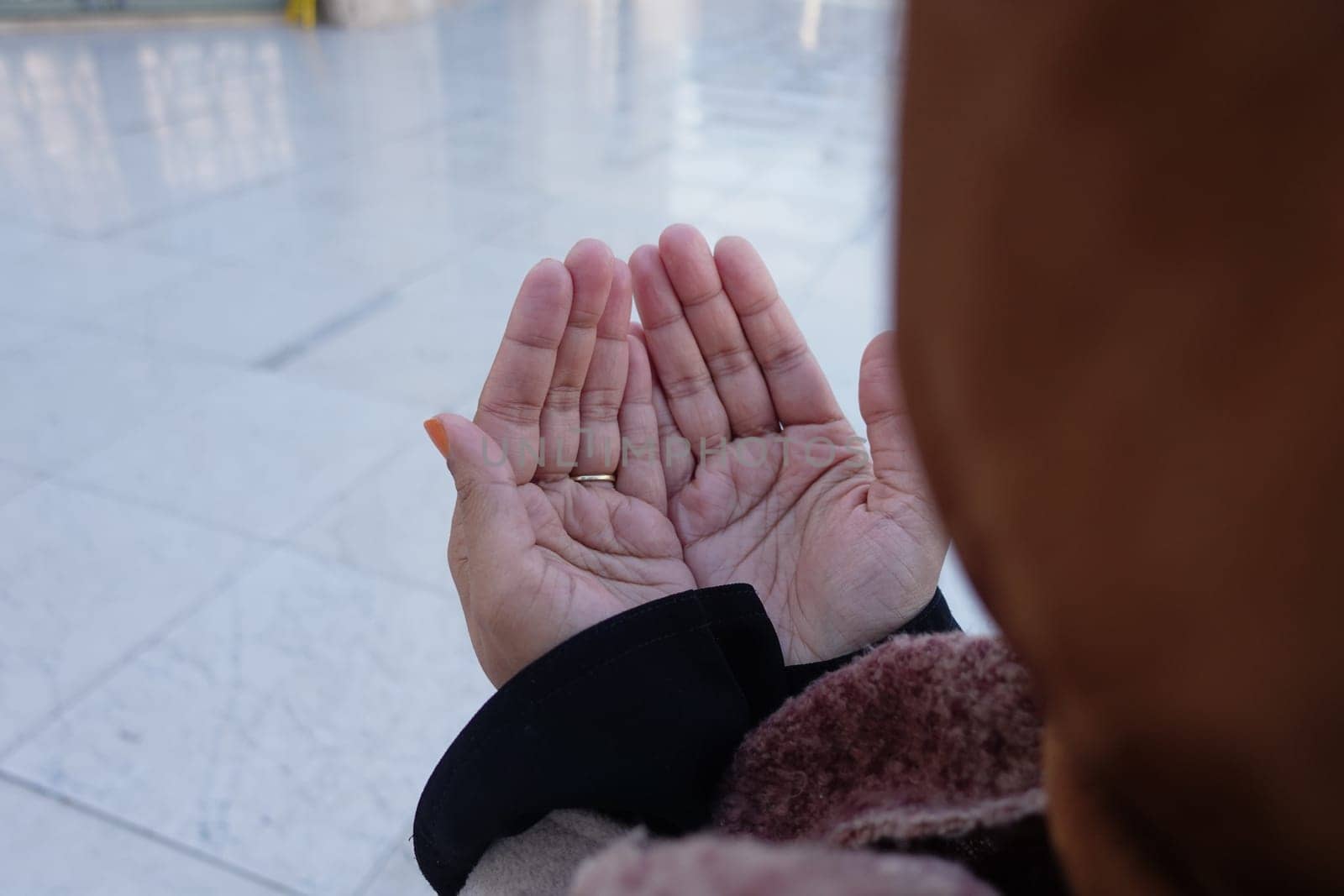 Muslim young woman in hijab is praying in mosque