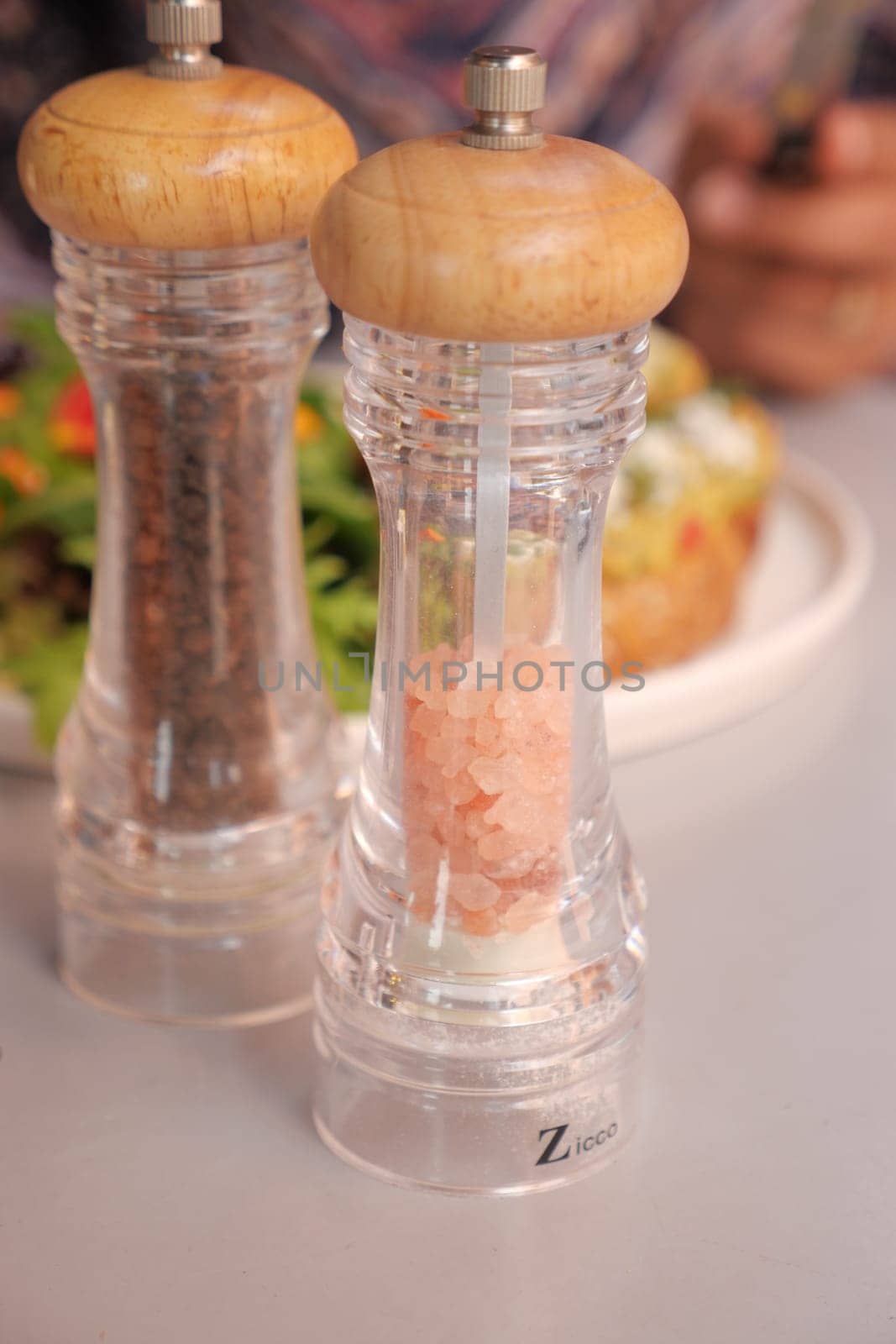 Elegant salt and pepper grinders are beautifully showcased alongside a fresh, vibrant salad